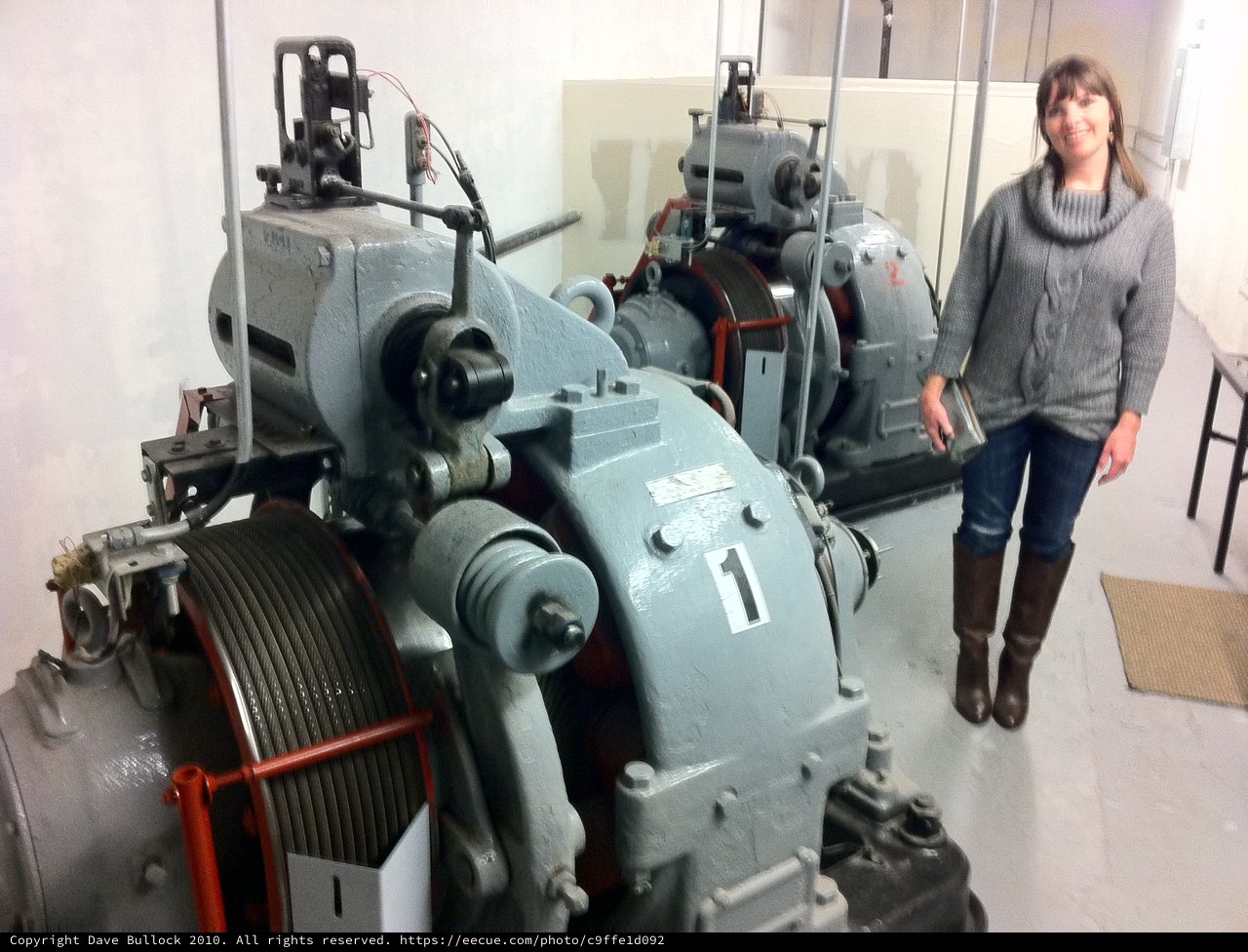 Woman Poses Beside Historic Elevator Machine Room Equipment
