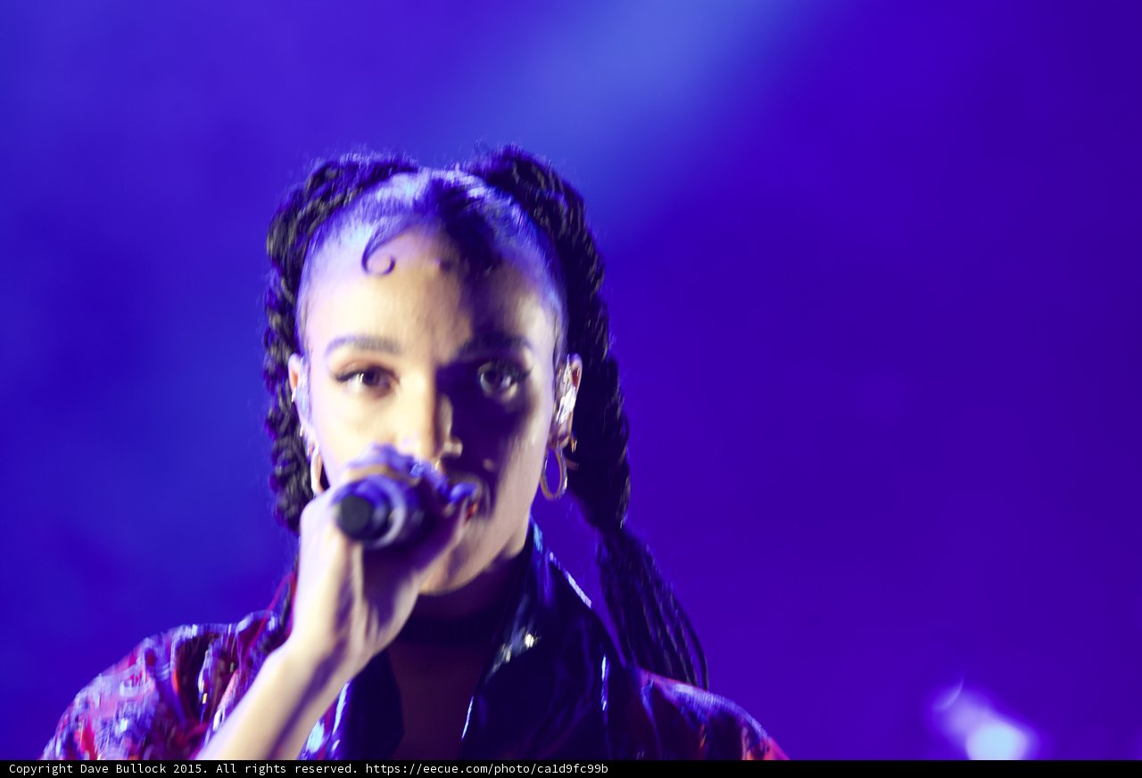 FKA twigs Intimate Portrait Direct Intense Gaze Baby Hairs Swirls Cat-Eye Makeup Hoop Earrings Septum Ring Braided Ponytails Framing Face Black Choker Kimono Purple Blue Lighting