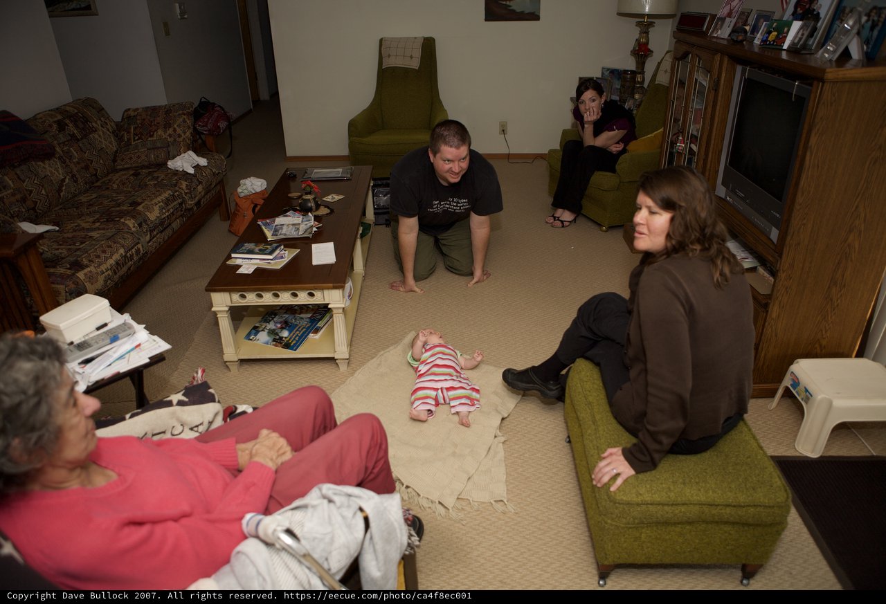 Family Gathering Around Newborn Baby in Living Room