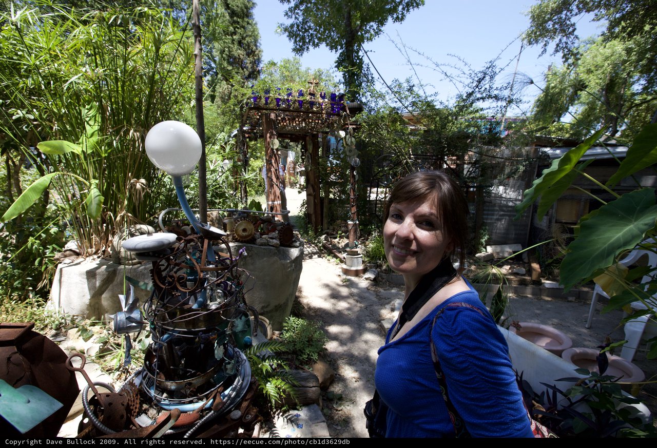 Woman Smiling Among Eclectic Junk Art Garden