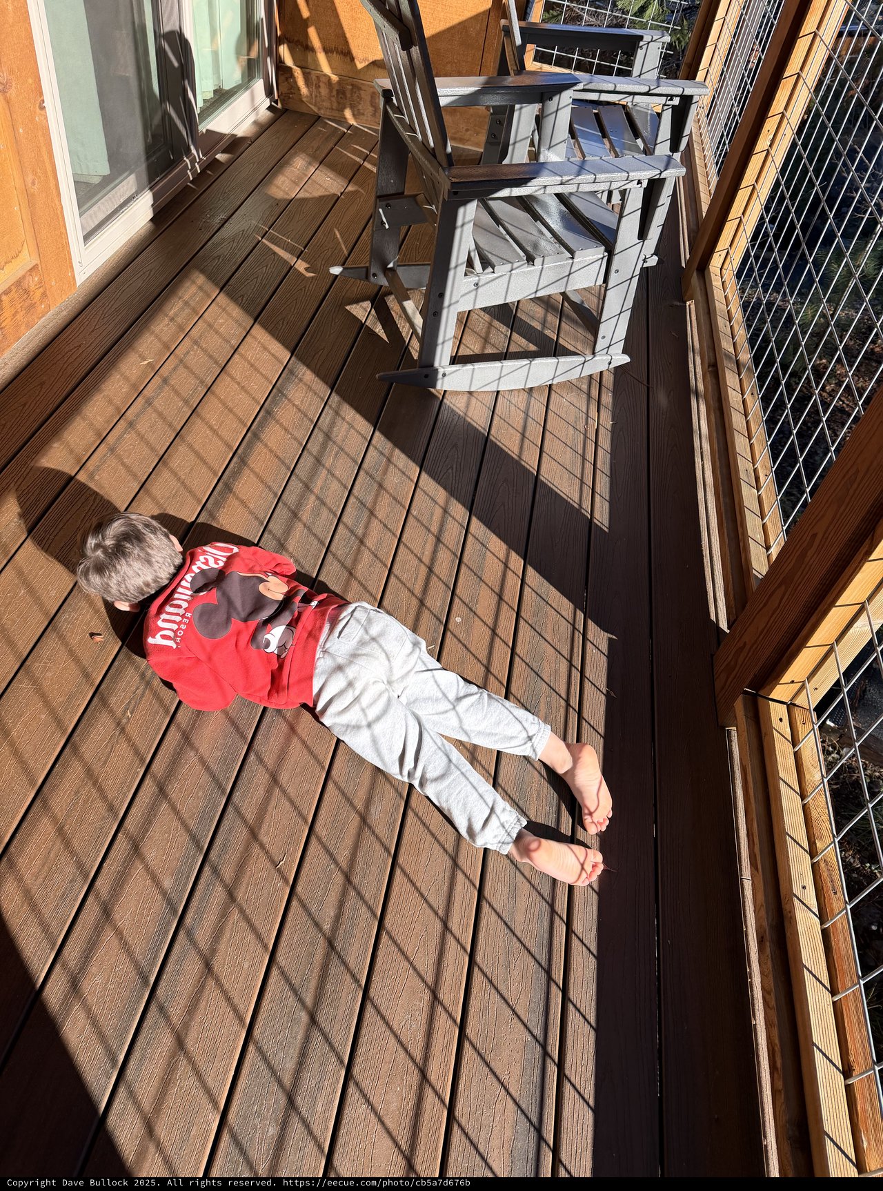 Child Soaking Up Winter Sun on Wooden Deck