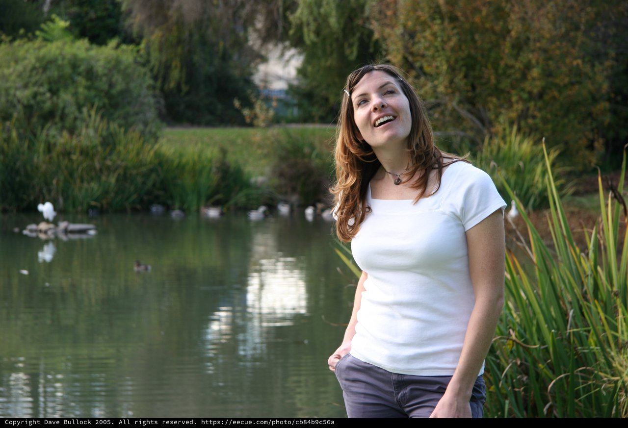 Joyful Woman Laughing by a Tranquil Park Pond