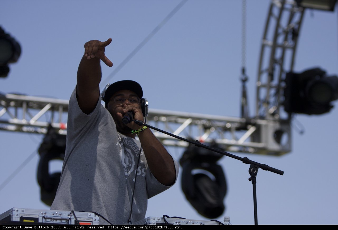 Pointing to the Skies Caption: An electrifying performance by the singer, with the blue sky and bright light shining down on him as he points up with his mic.