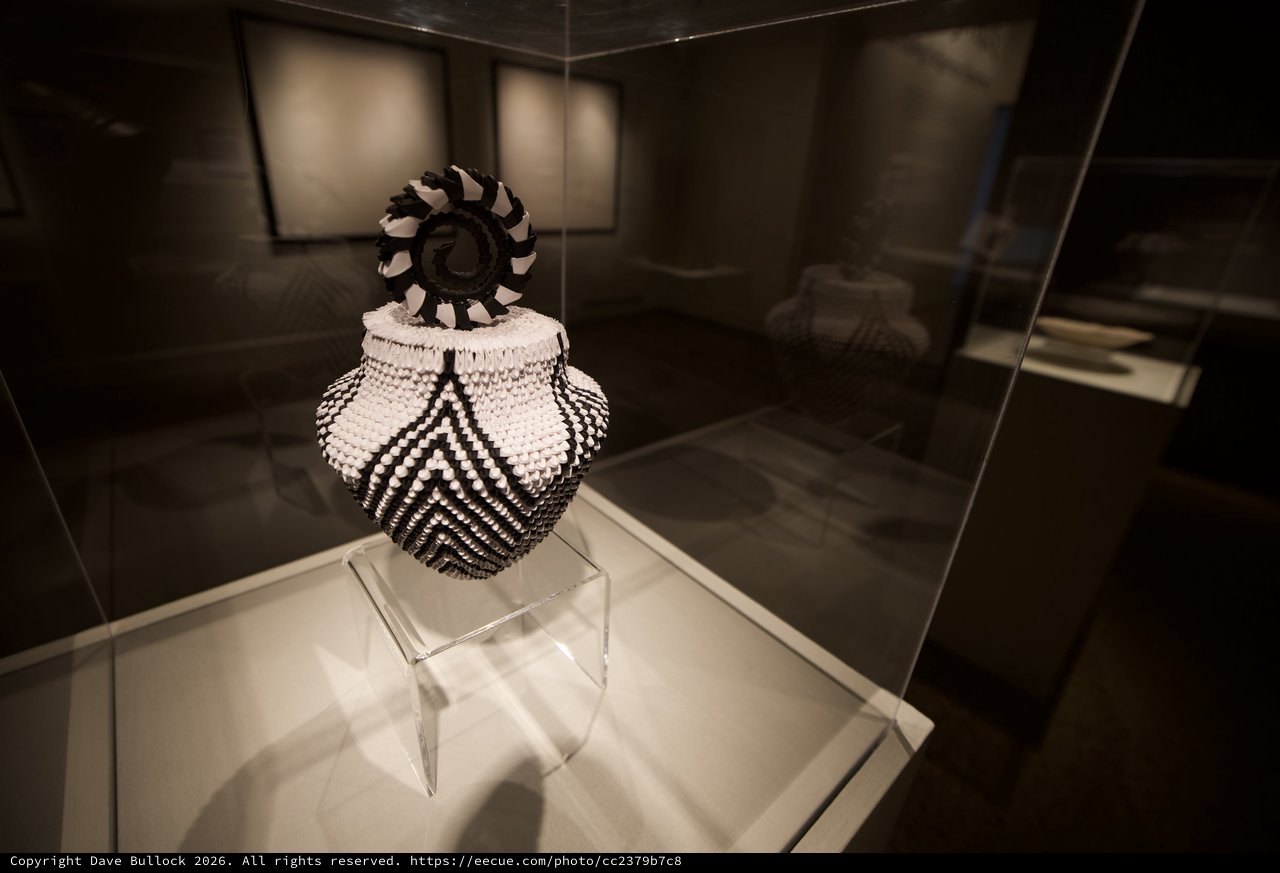 Traditional Beaded Vessel with Decorative Finial in Museum Display