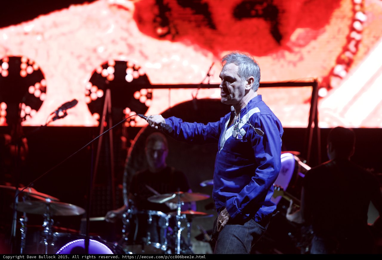 Morrissey Swinging Mic Cord Blue Shirt Drummer Glasses Behind LED Drum Head Two Circular Lights Red Screen