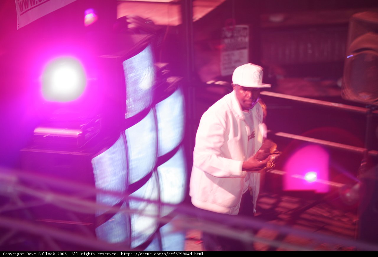 Entertainer in White Suit Performs in Front of Large Screen