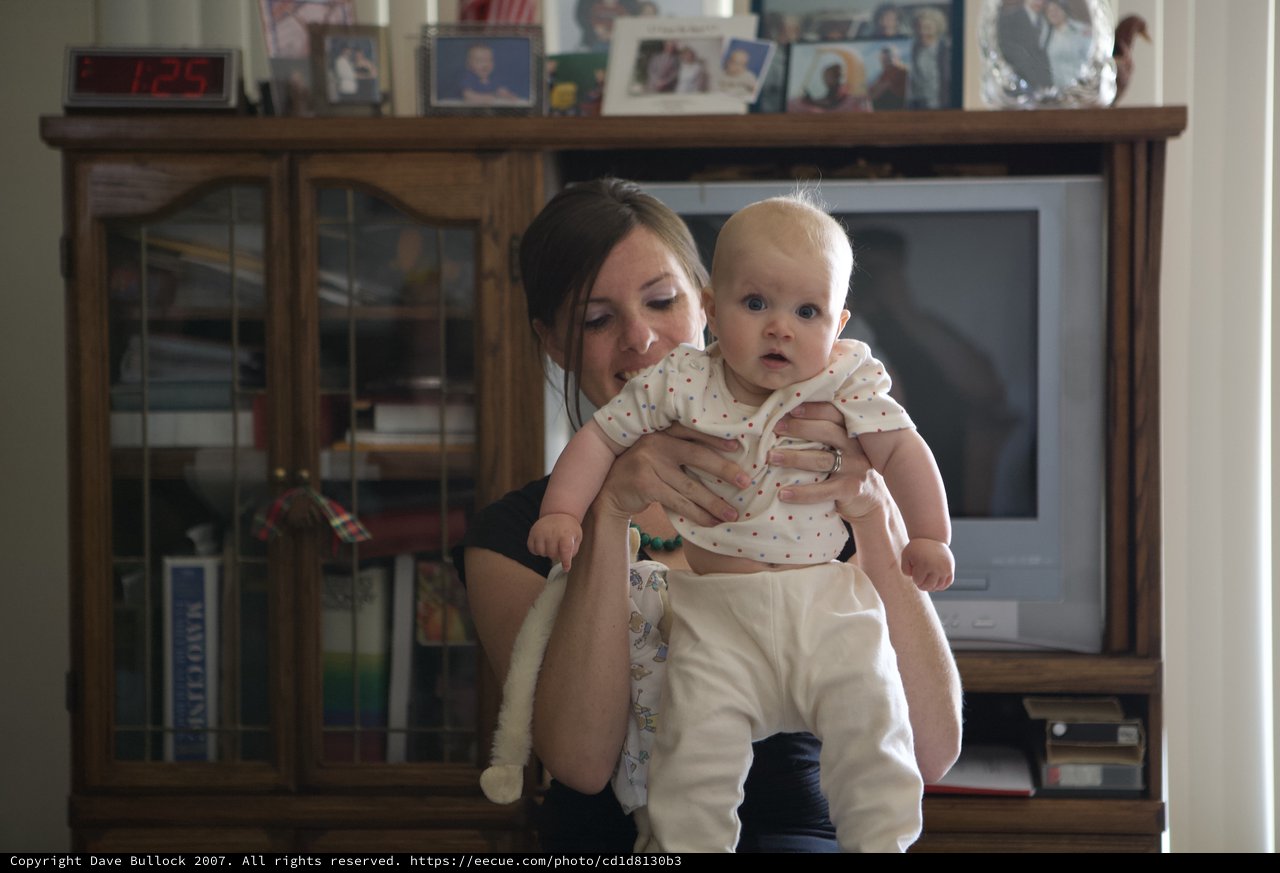 Mother Holds Wide-Eyed Baby in Family Living Room