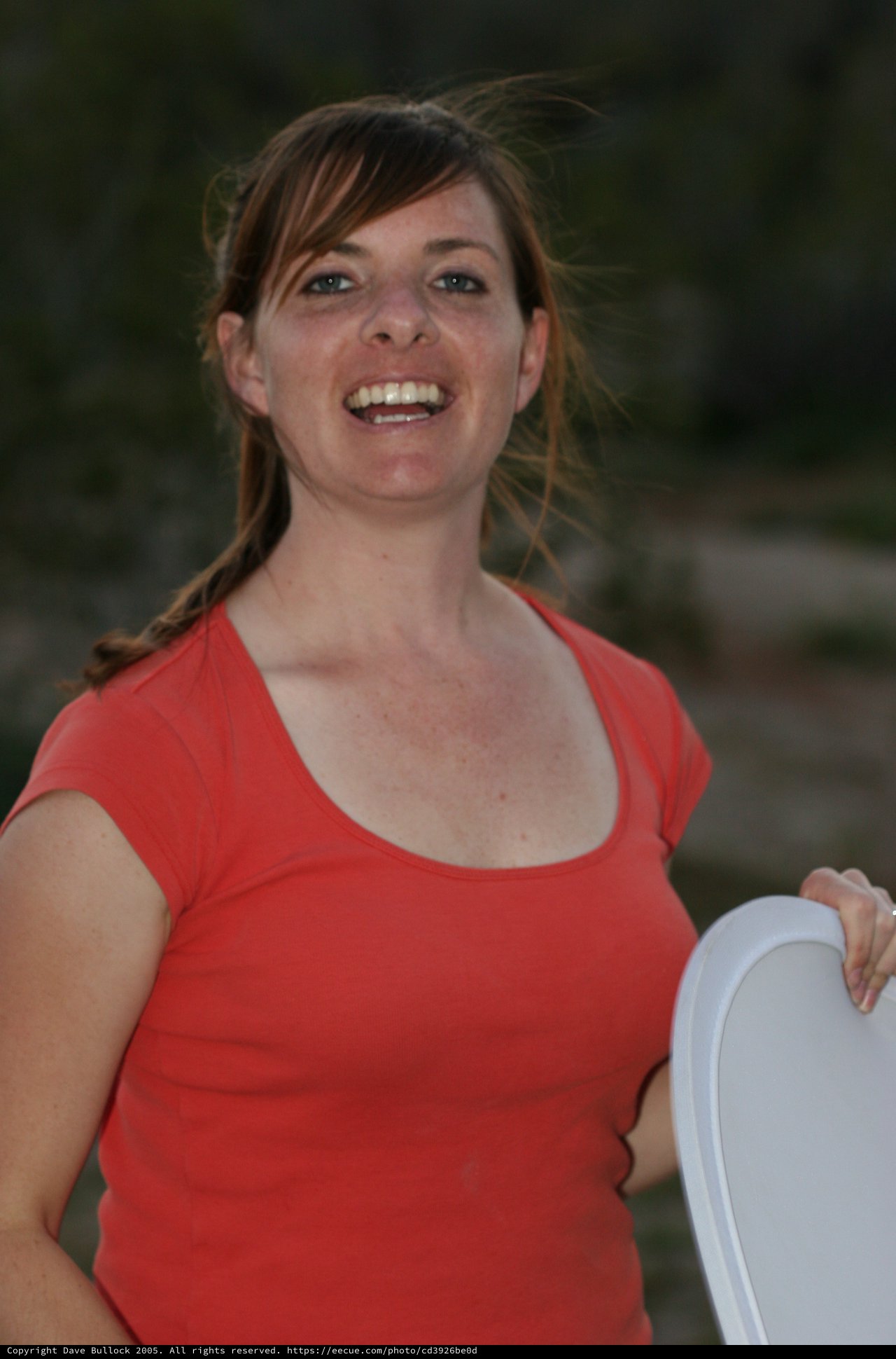 Laughing Woman in Red Top Holds Frisbee Outdoors