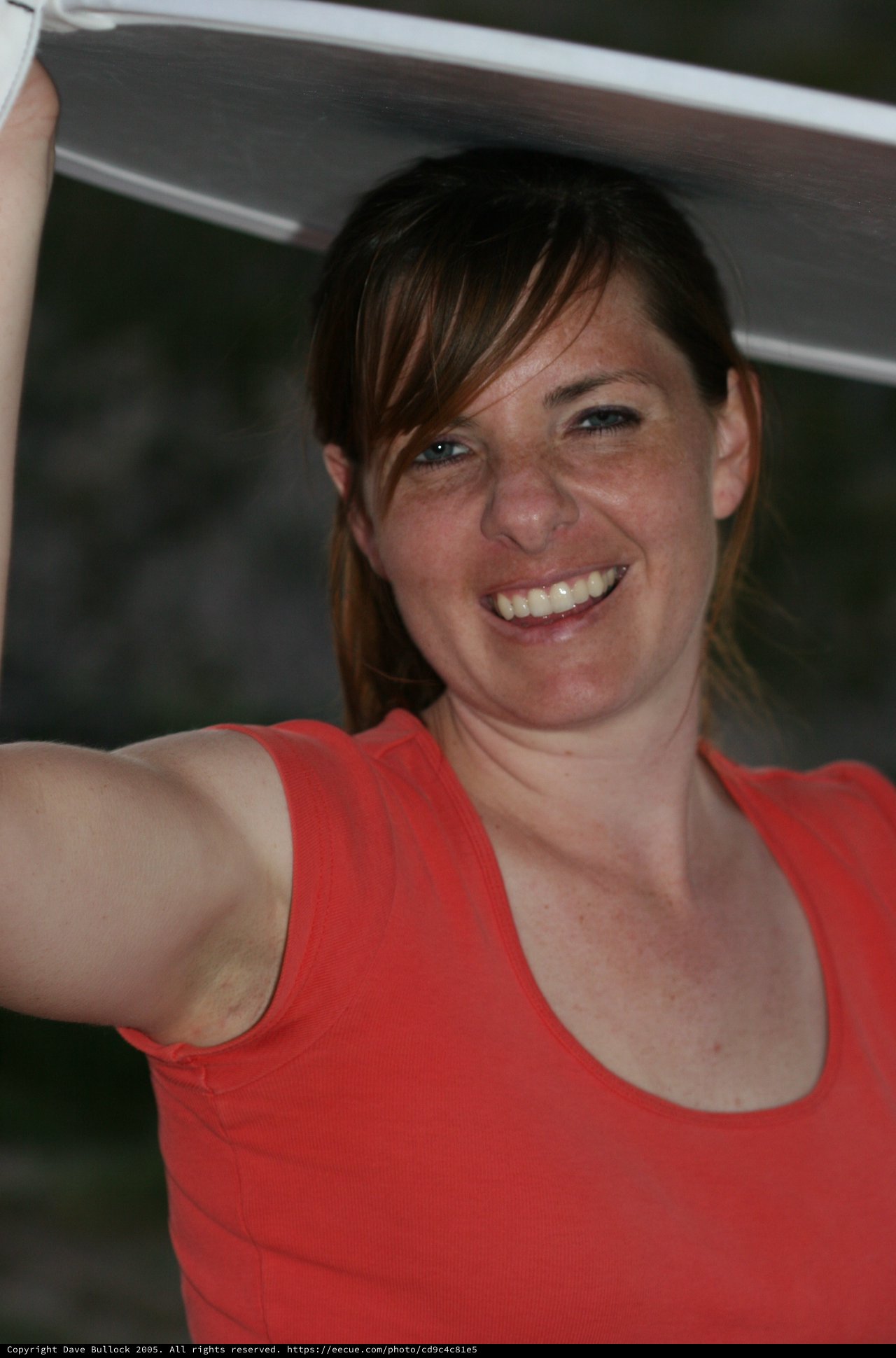 Joyful Woman Holding Up a White Panel Outdoors