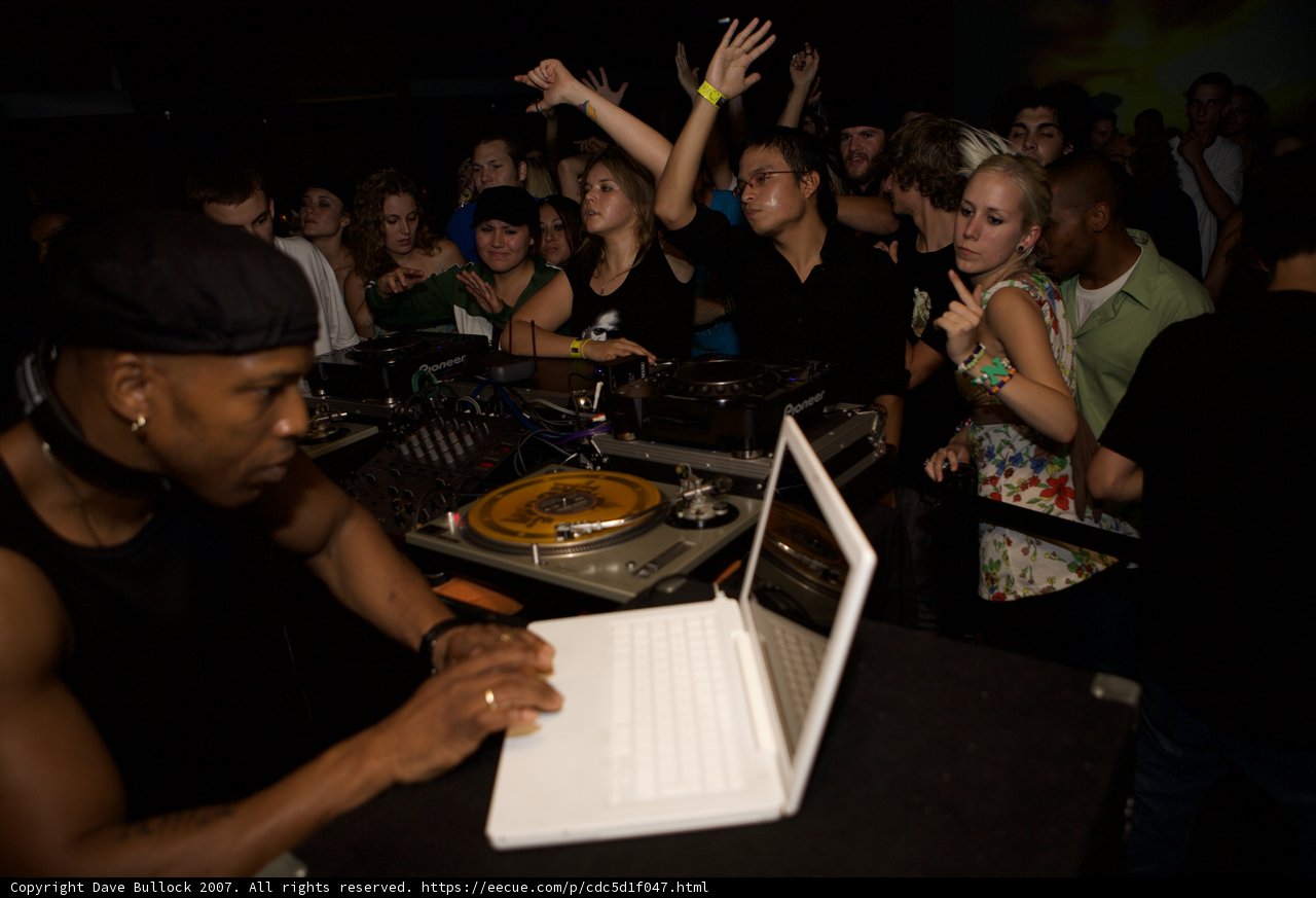 Man in Black Shirt Working on Laptop at Nightclub