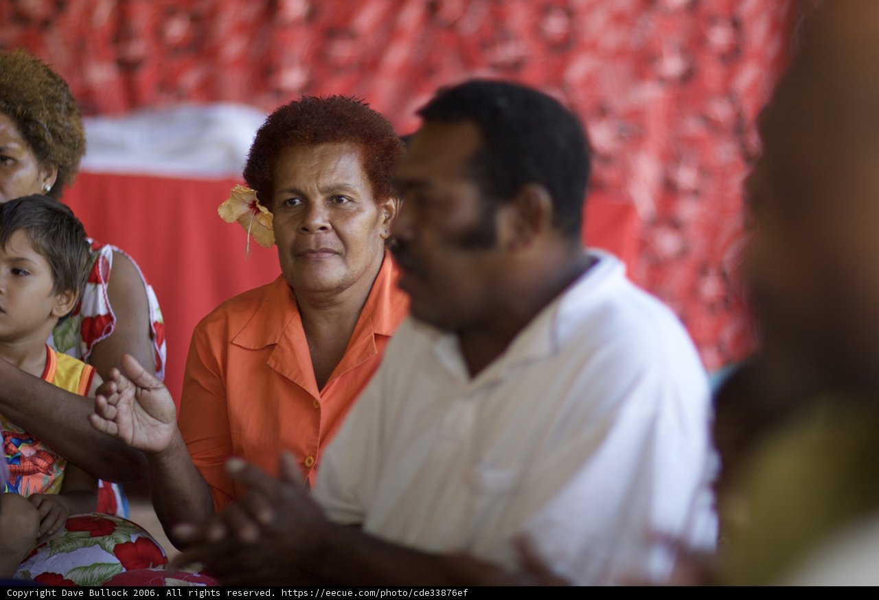 Gathering of Friends Caption: Four men, including two children, sit around a table, their hands and fingers entwined, enjoying each other's company in Fiji in 2006.