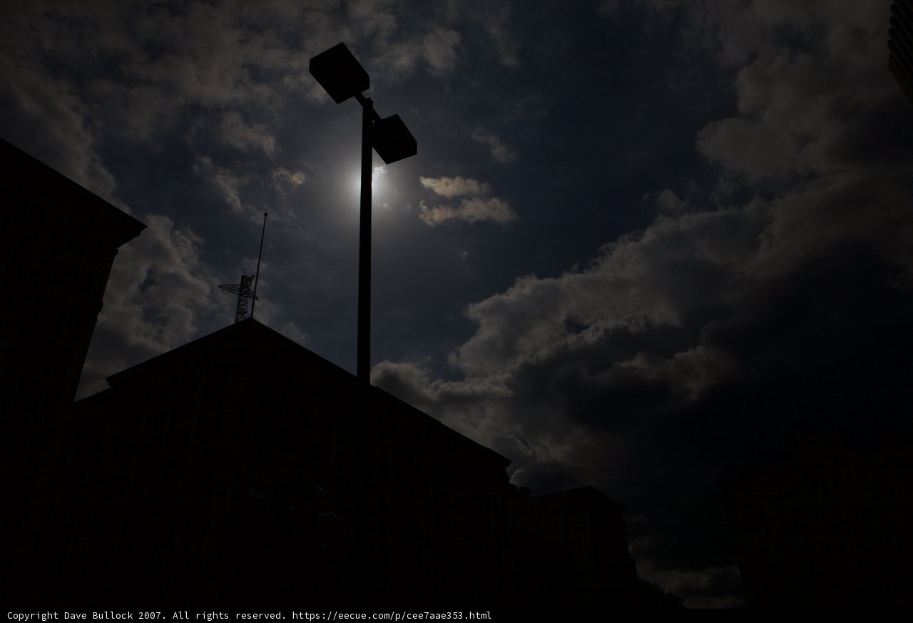 Silhouette of a Lamppost Against Cloudy Night Sky