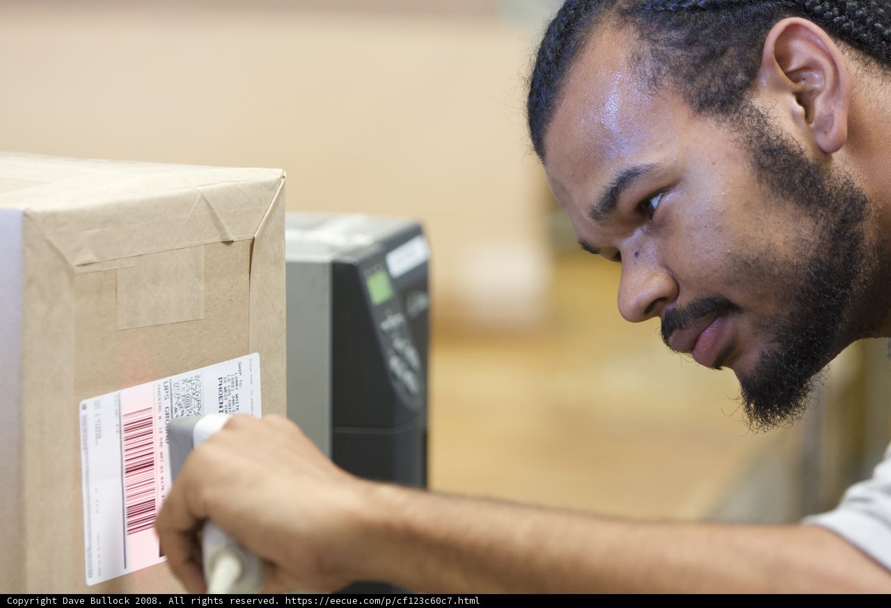 Curious Man Examining Barcode on Cardboard Box