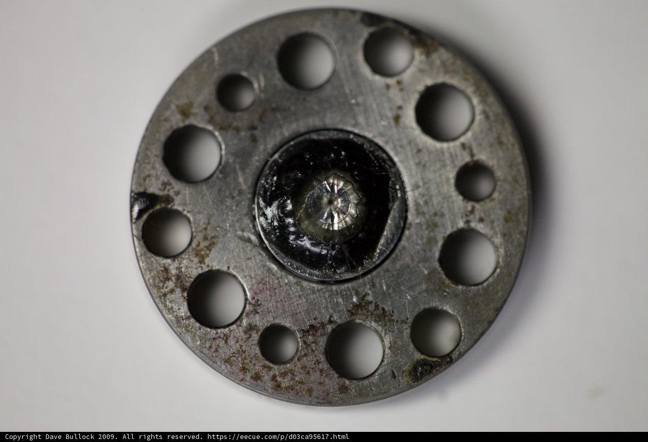 Close-Up of Spoked Metal Object Caption: This intricate metal object features spokes and holes, resembling an alloy car wheel or rotor. Its design is reminiscent of a coil or spiral, with possible use in the transportation industry.