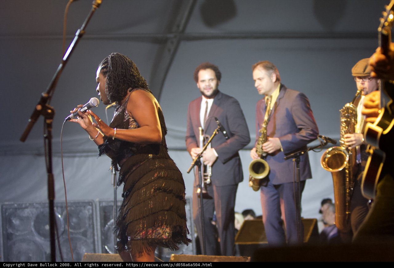 Woman in Black Dress Sings with Musical Band on Stage