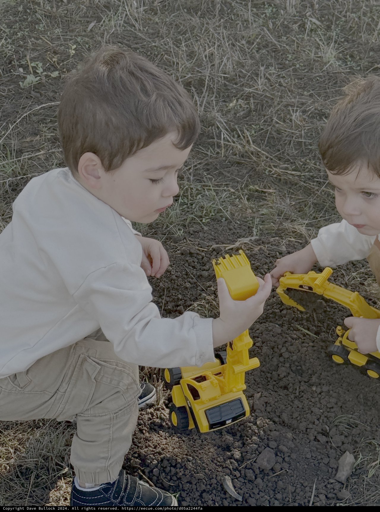 Two Young Boys Playing with Yellow Toy Trucks