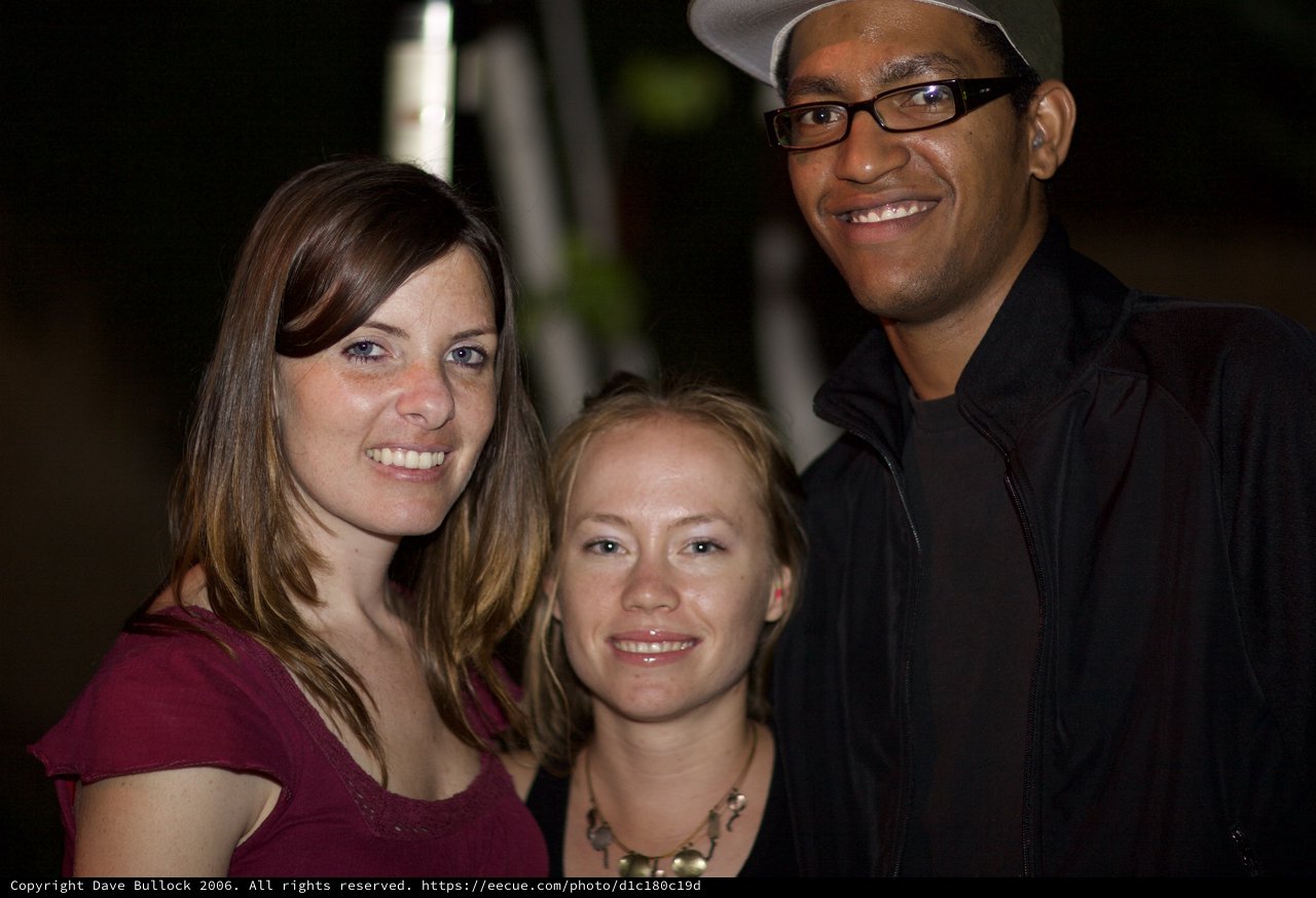 Three Friends Smiling Together at Night Event
