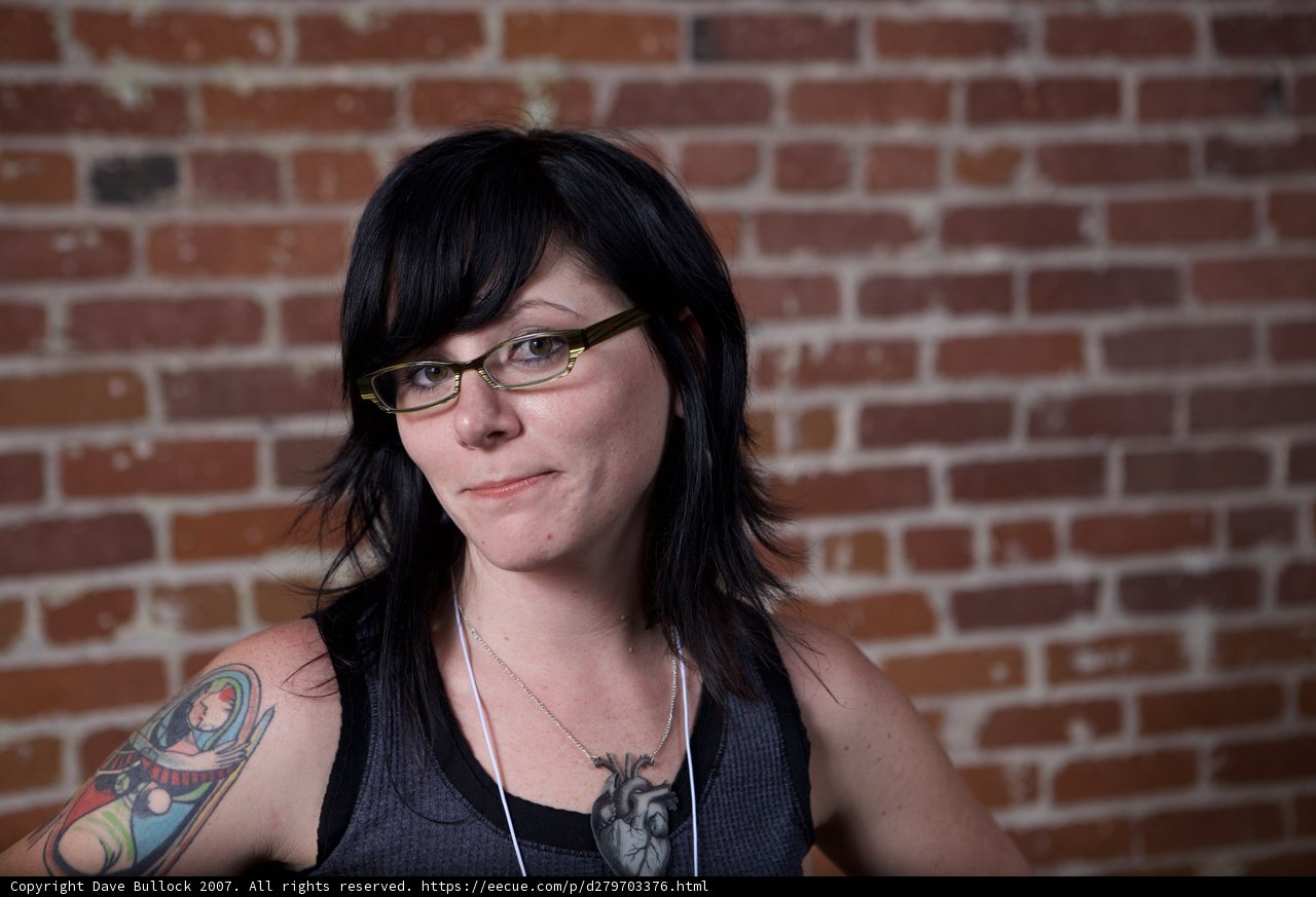 Tattooed Woman Stands Tall Against Brick Wall