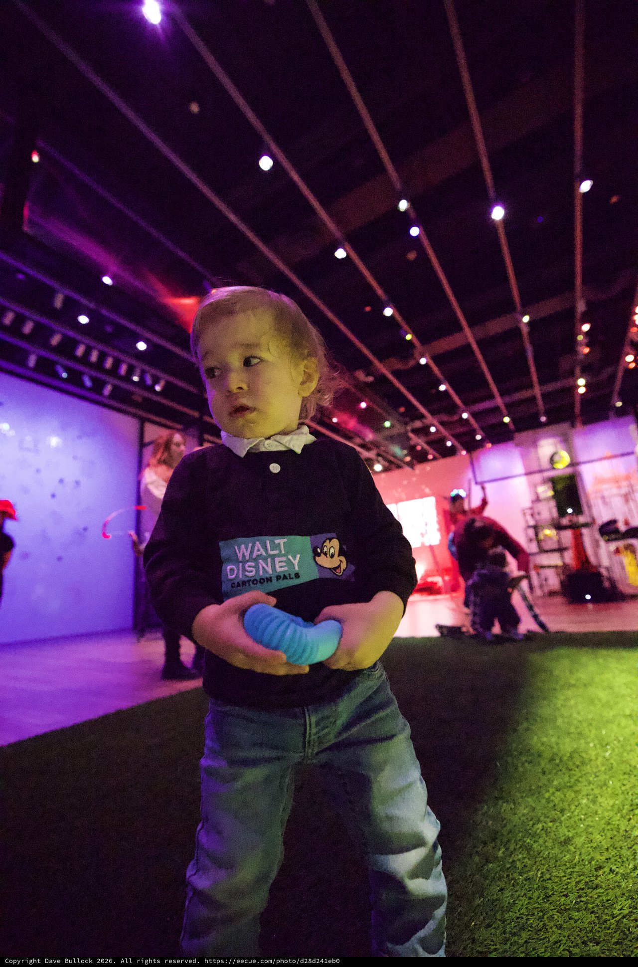 Young Child at Baby Rave Event Under Neon Lights