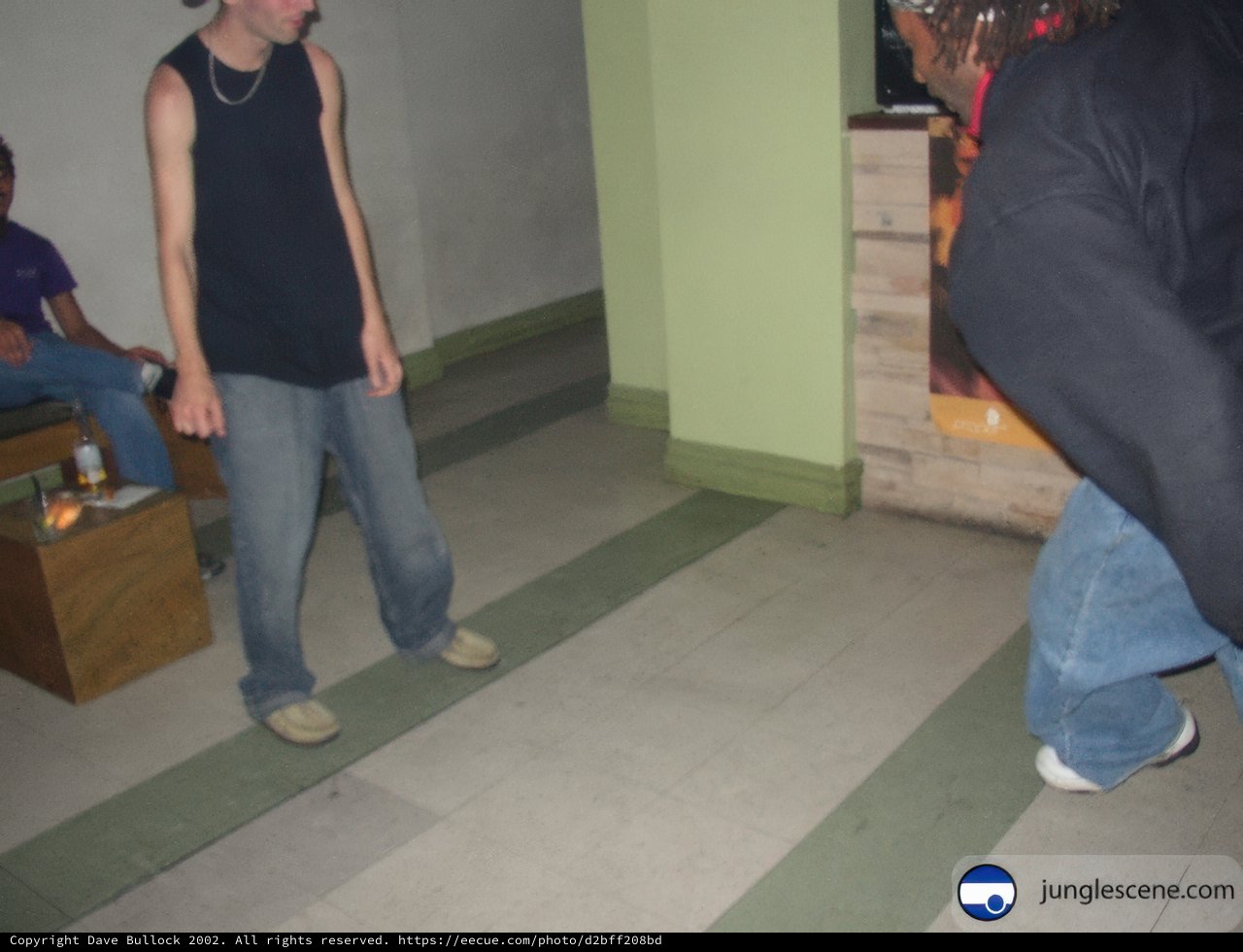 Black-Shirted Man Walking Barefoot on Plywood Flooring