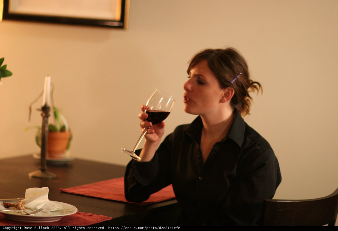Woman Savoring Red Wine at Dinner Table
