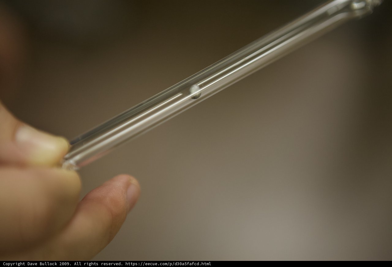 A person holding a clear tube with metal piece