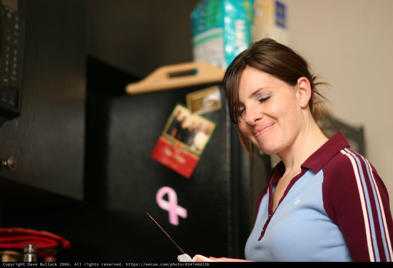 Woman Smiling in Kitchen Near Refrigerator