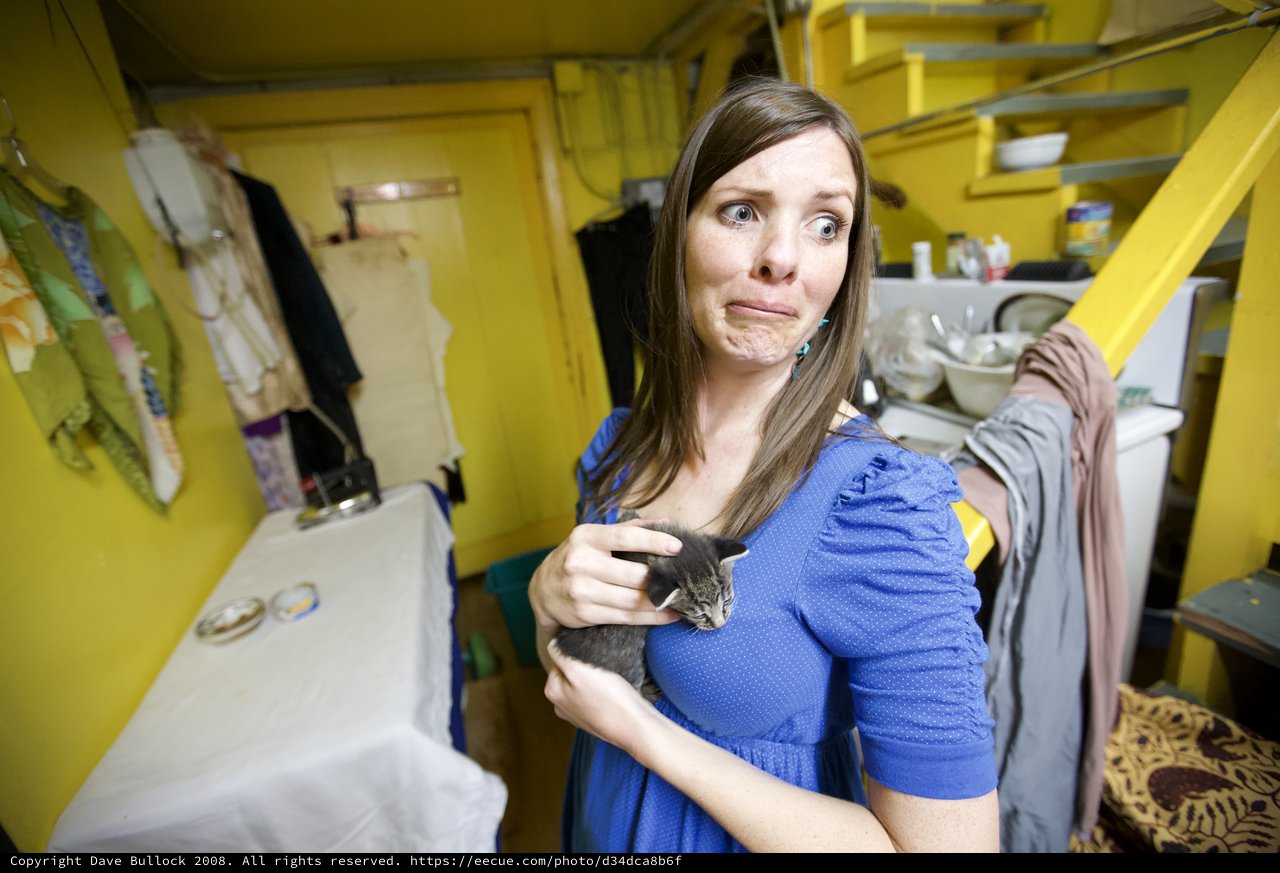 Woman Holds Tiny Kitten with Apprehensive Expression