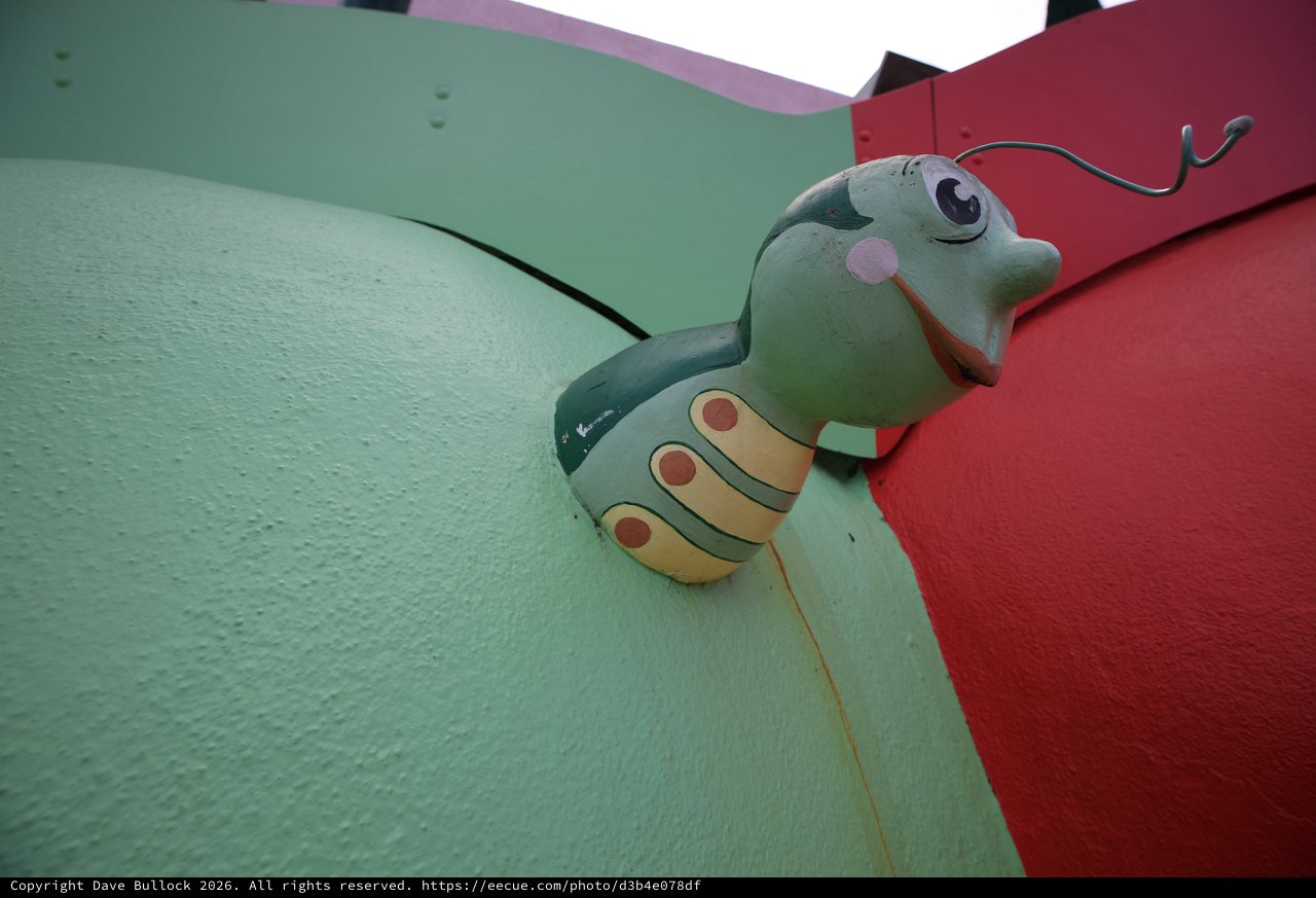 Whimsical Green Caterpillar Sculpture on Colorful Wall