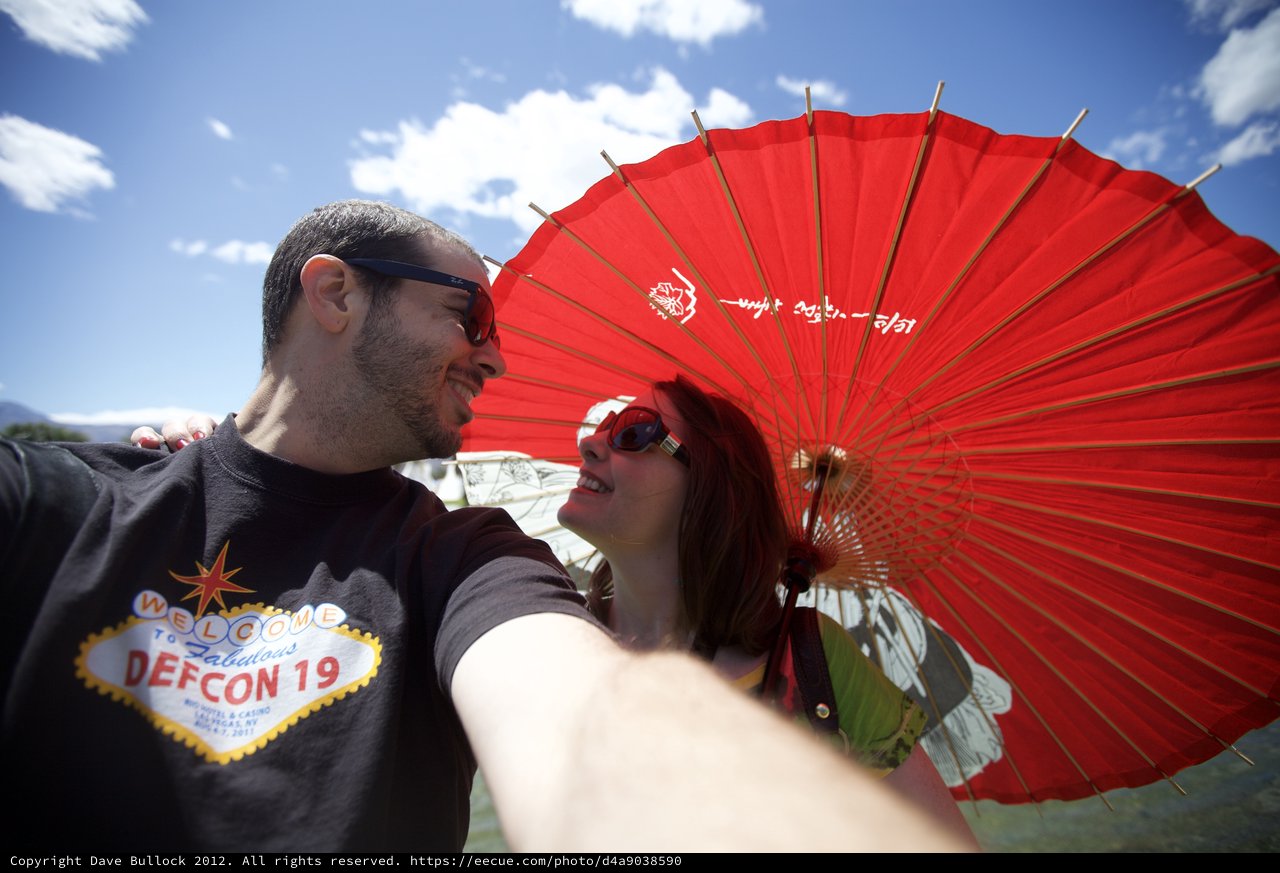 Couple Shares Joyful Moment Under Red Parasol