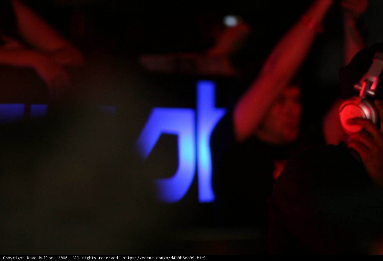 Grooving to the Beat Caption: A man wearing headphones vibing to the music at a crowded night club in the city.