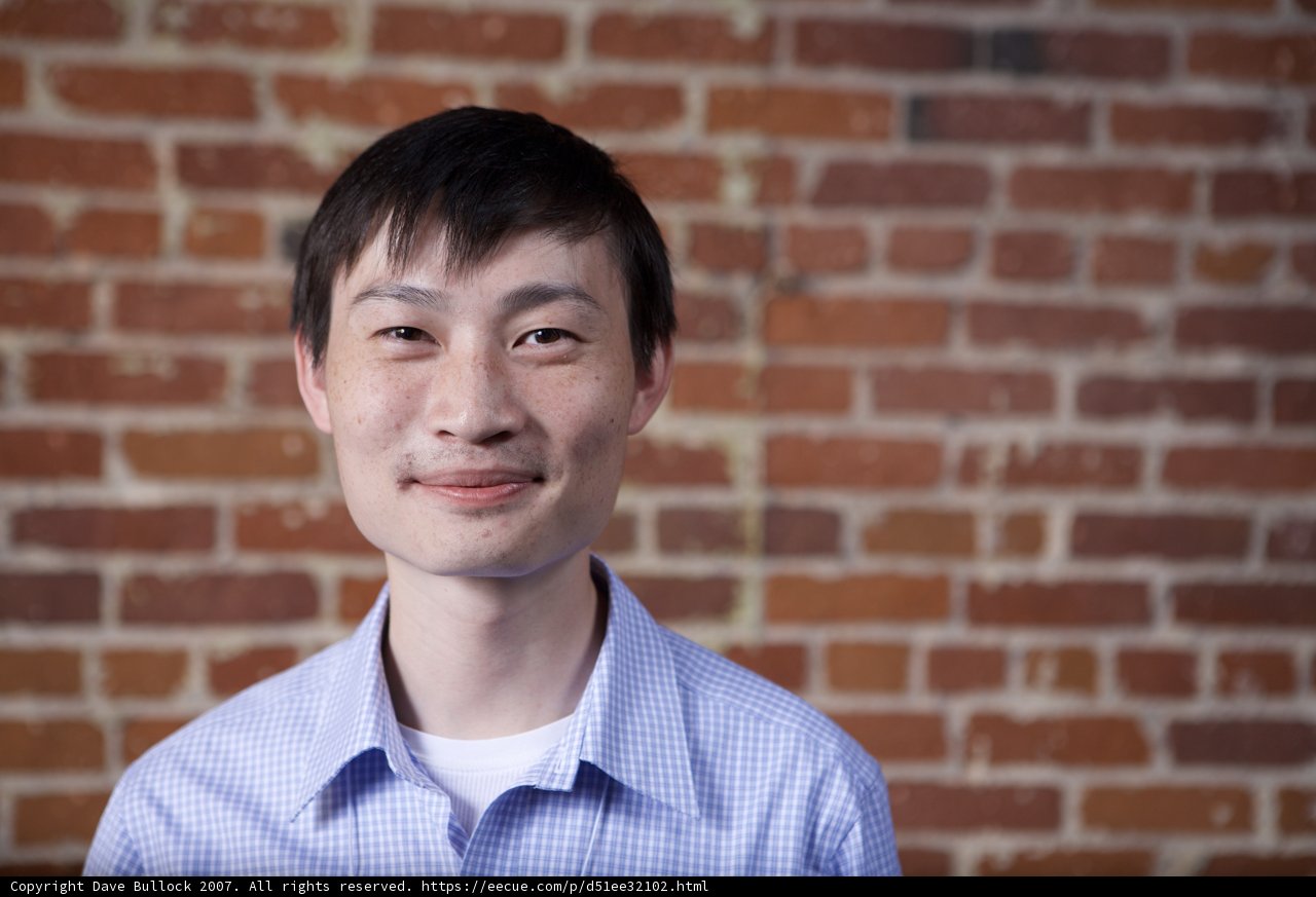 Smiling Man Poses in Front of Brick Wall