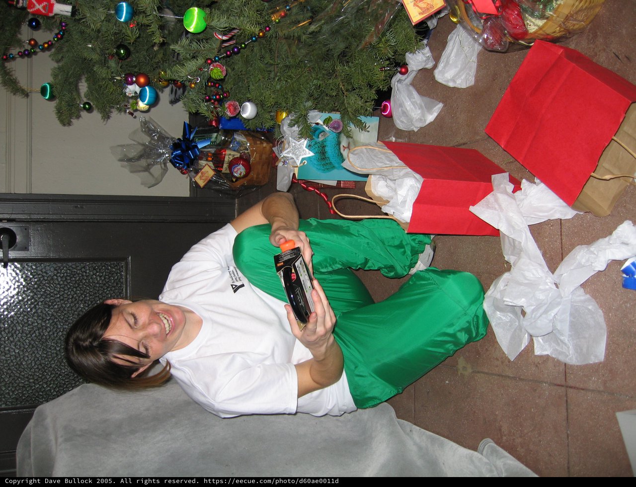 Joyful Woman Unwrapping Christmas Gifts by Tree