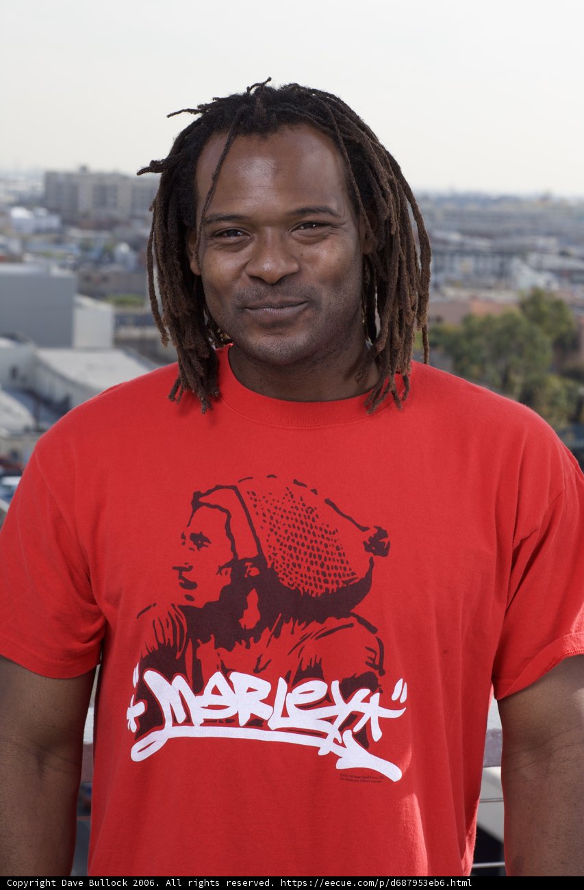 Red Shirted James Poses in Front of a Building