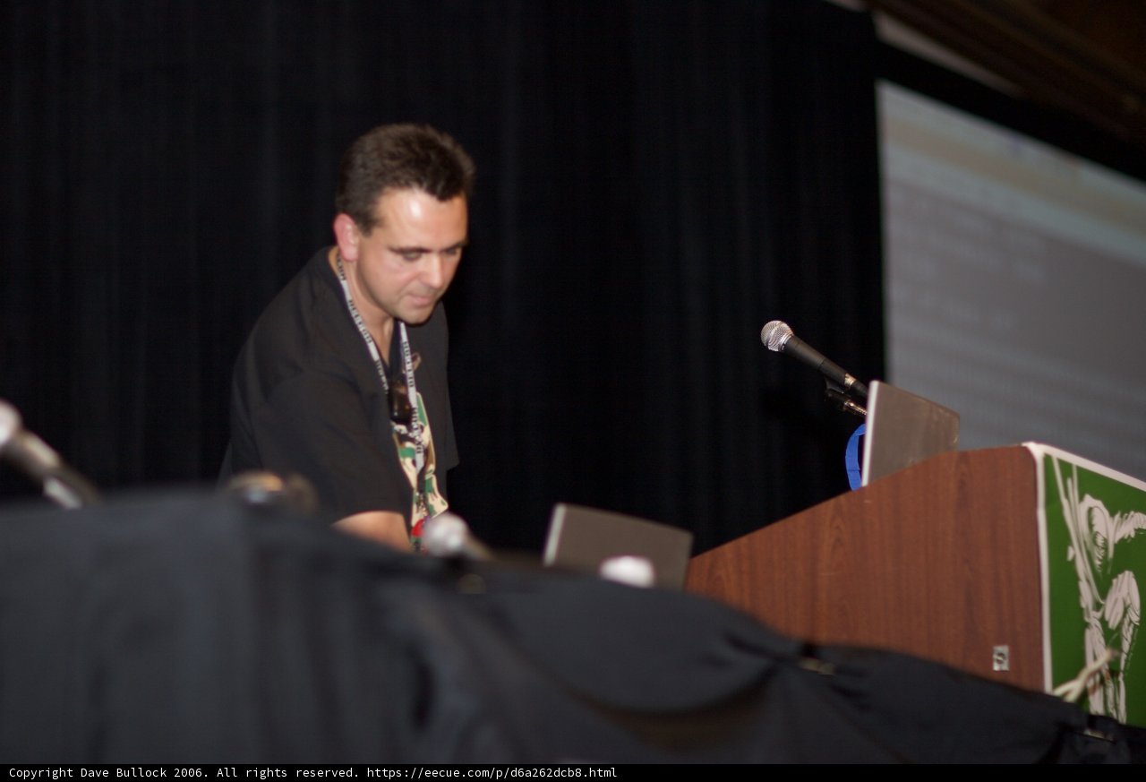 Man Giving a Speech Behind a Podium with Two Laptops