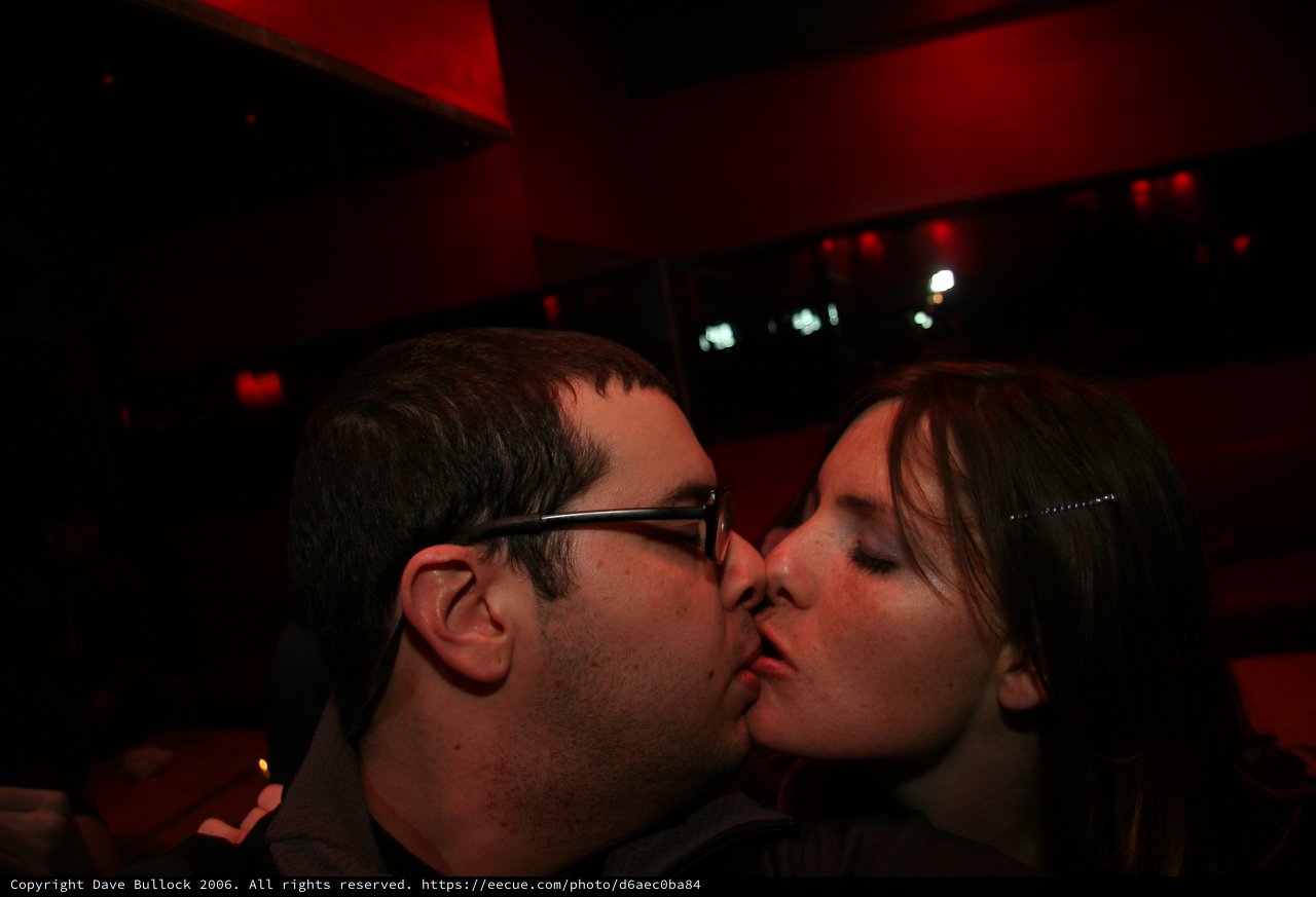 Couple Sharing a Kiss in Red-Lit Bar