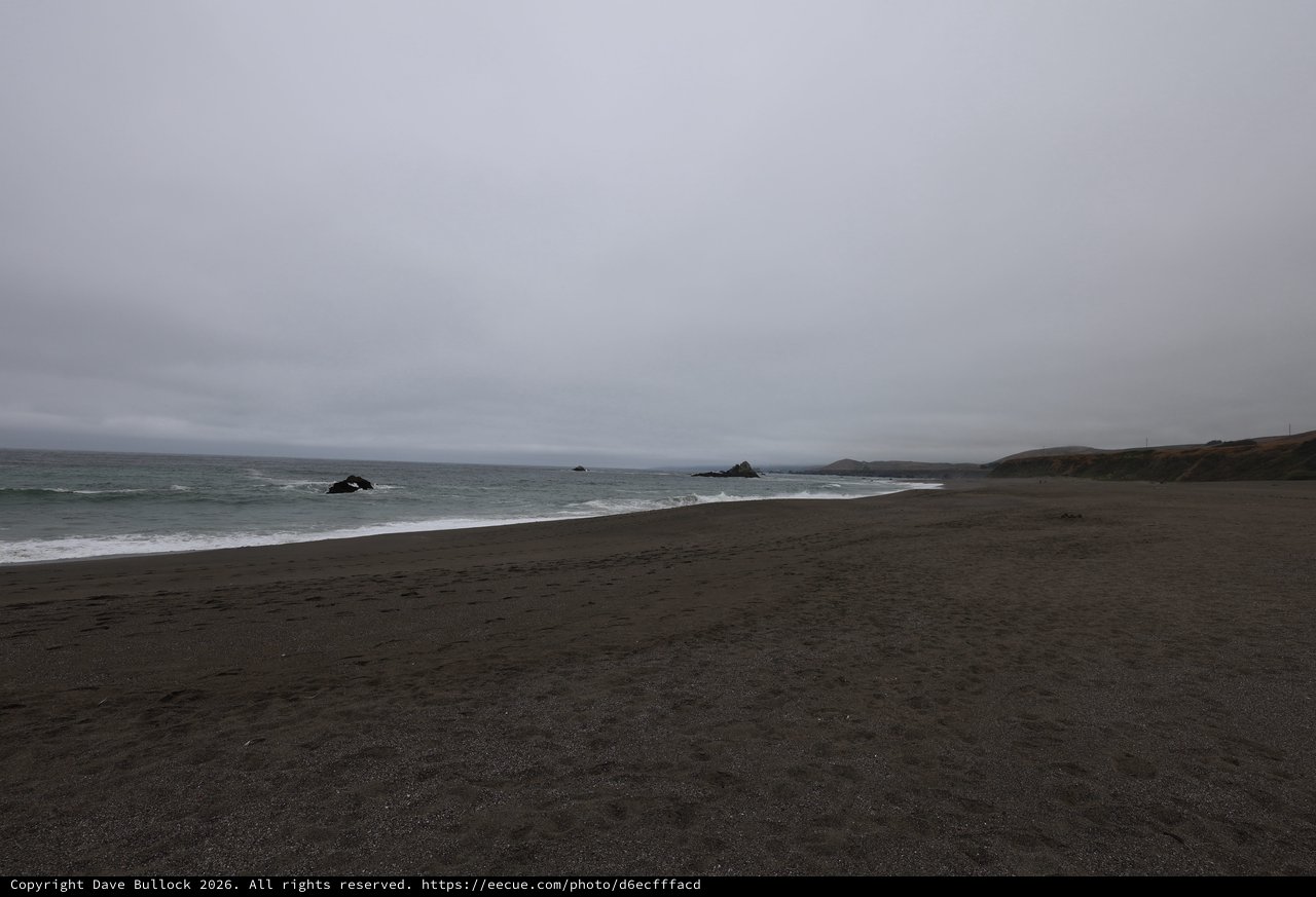 Moody Overcast Beach with Dark Sand and Ocean Rocks