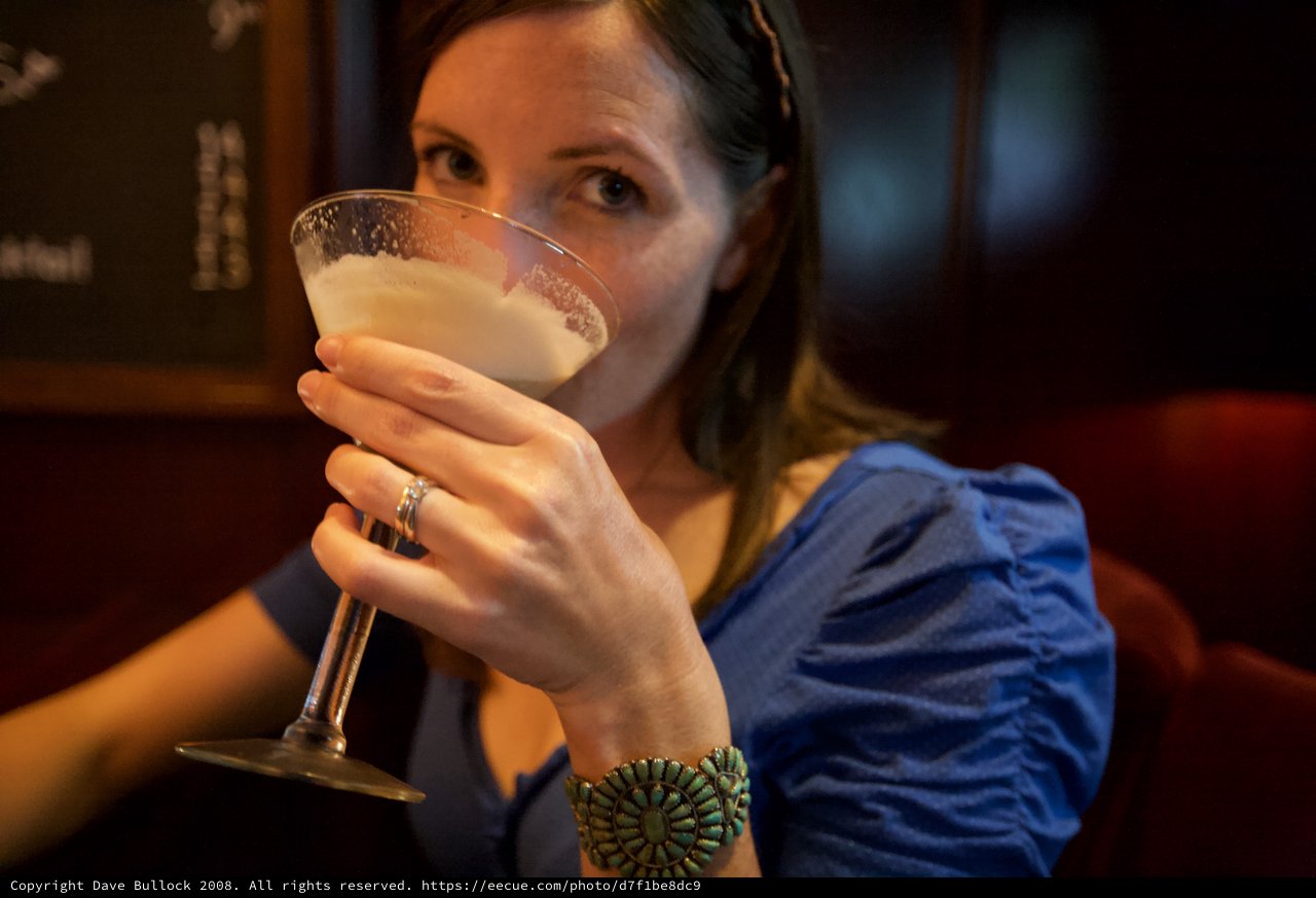 Woman Sipping Cocktail at Dimly Lit Bar