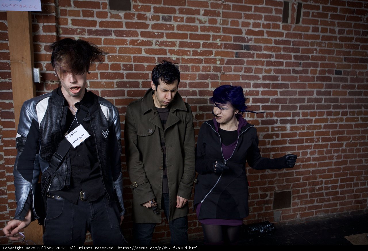Three People Posing Against a Brick Wall