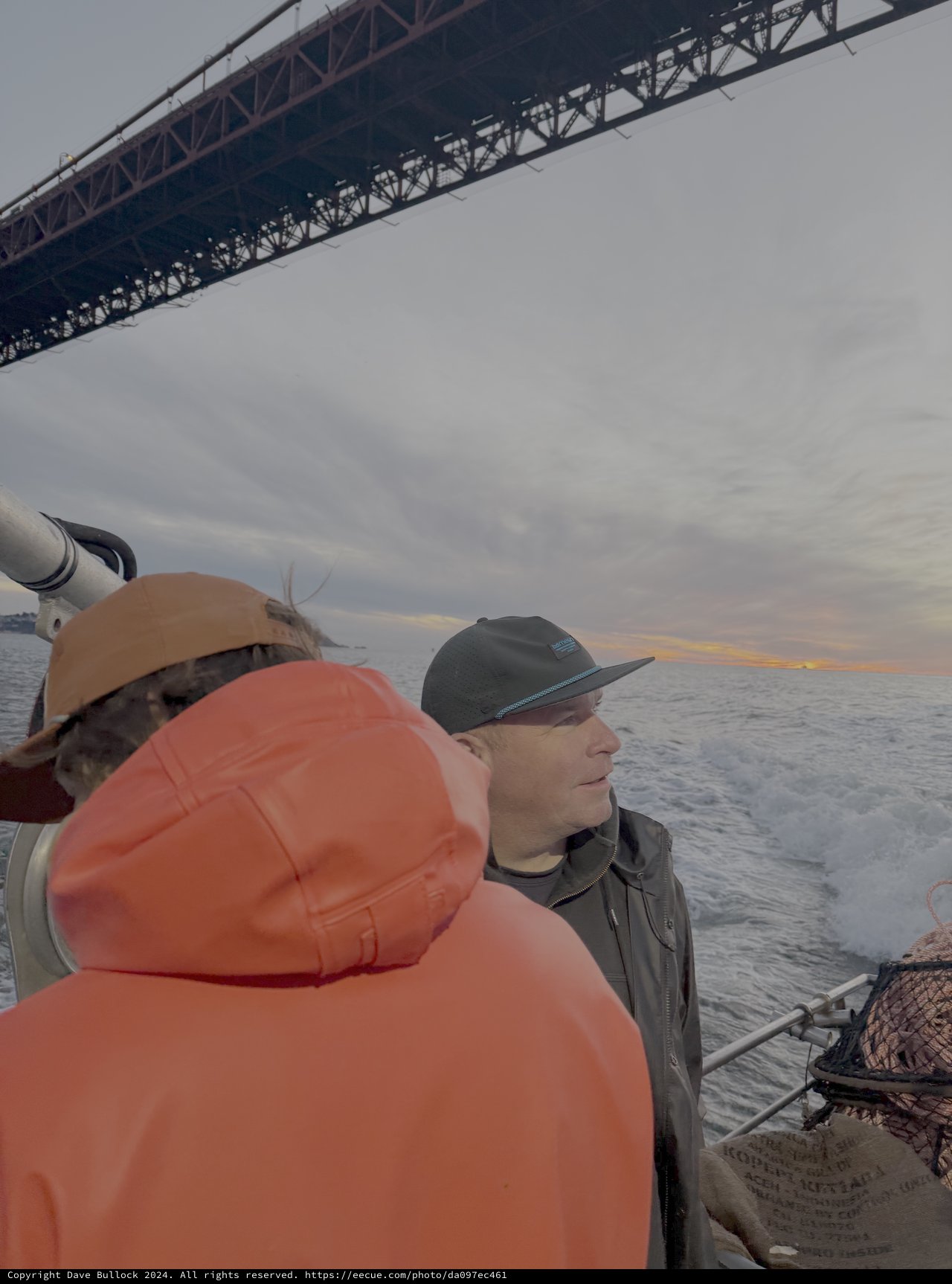 Boat Passengers Under Suspension Bridge at Dusk