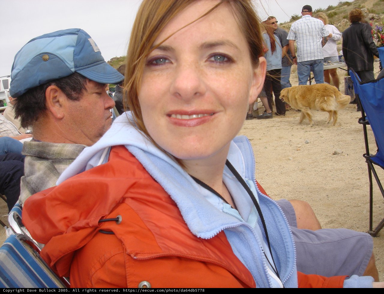 Woman Smiling at Sandy Outdoor Gathering Near Coast
