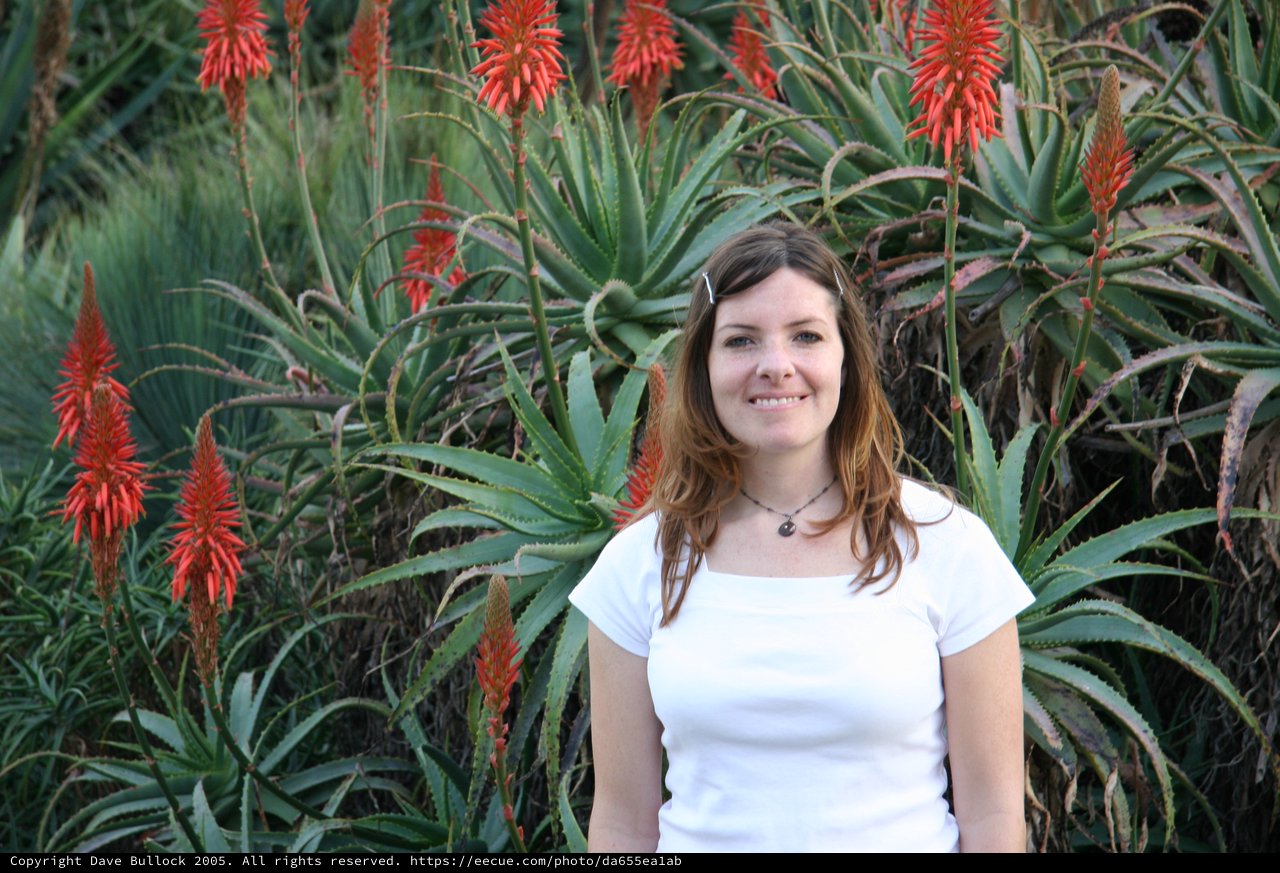 Smiling Woman Amid Blooming Aloe Vera Garden