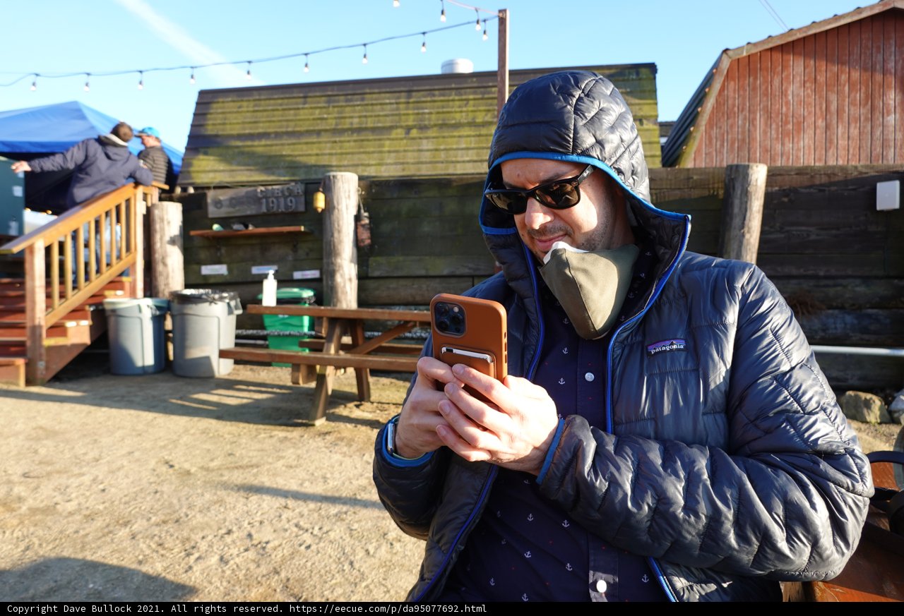 Man in Jacket and Hat Sitting on Rustic Bench