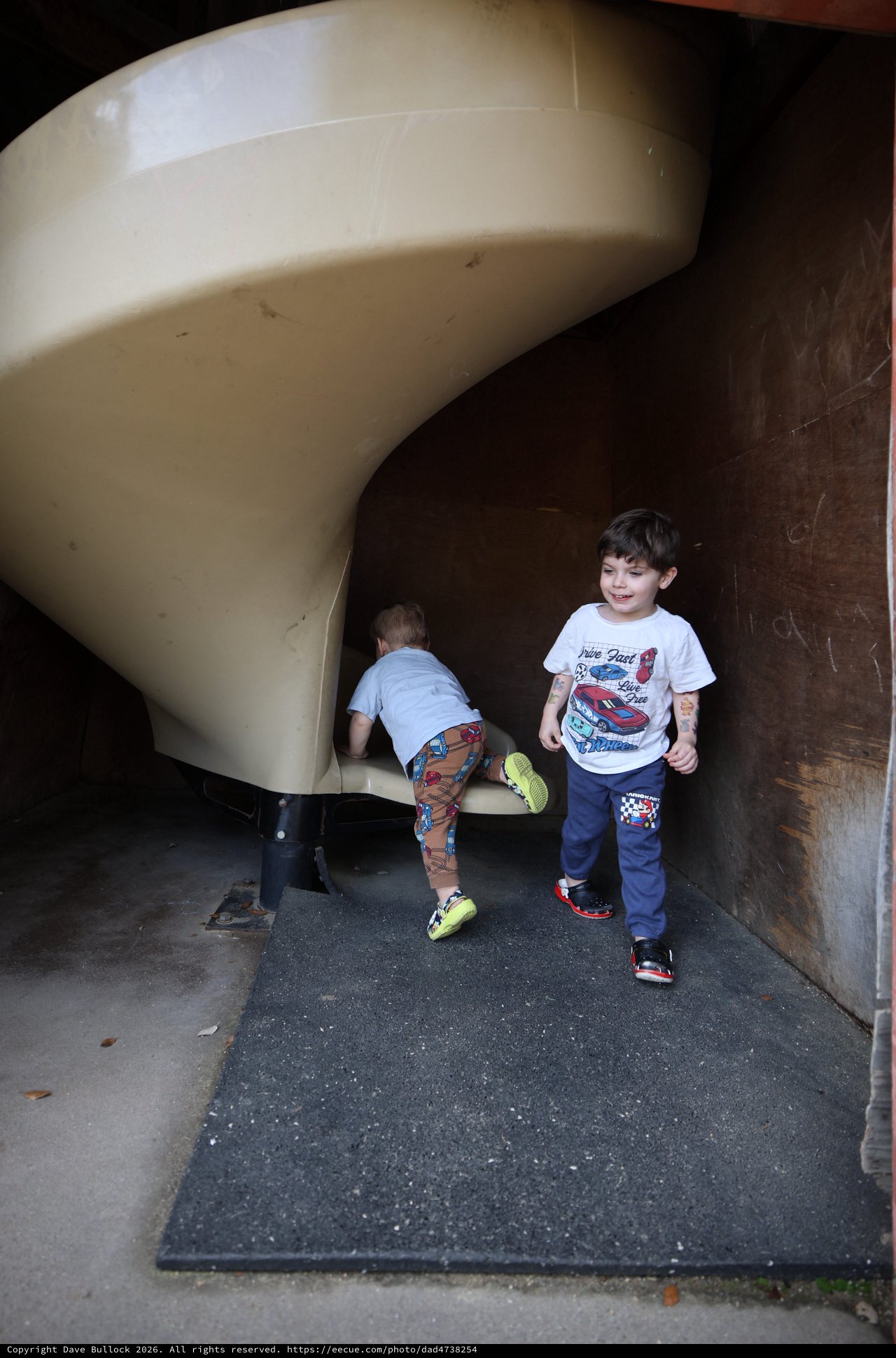 Children Playing on Curved Playground Slide at Dusk