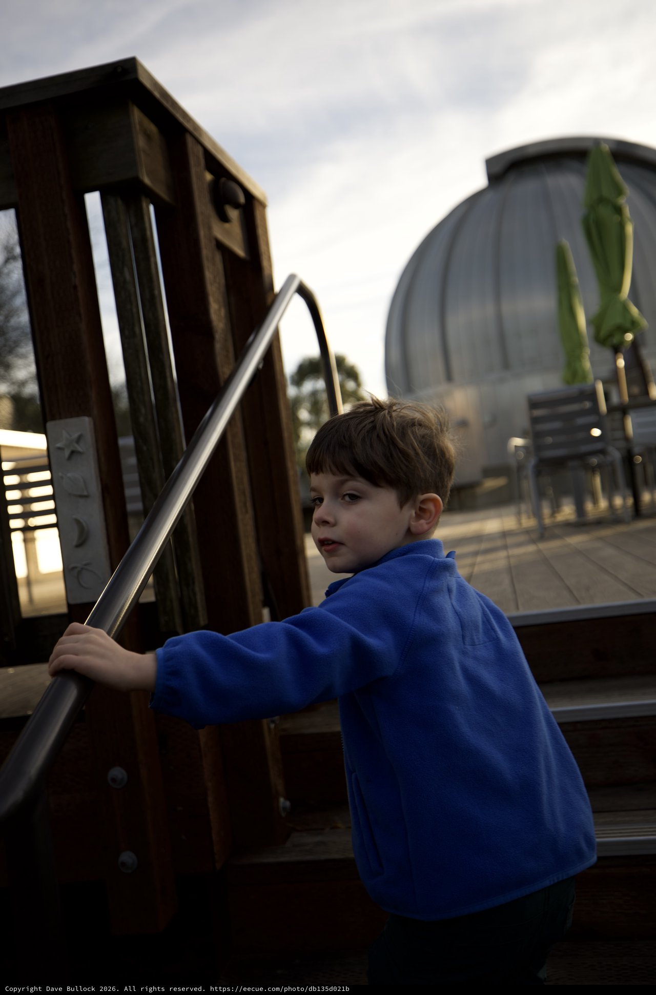 Young Boy at Modern Playground Structure at Dusk