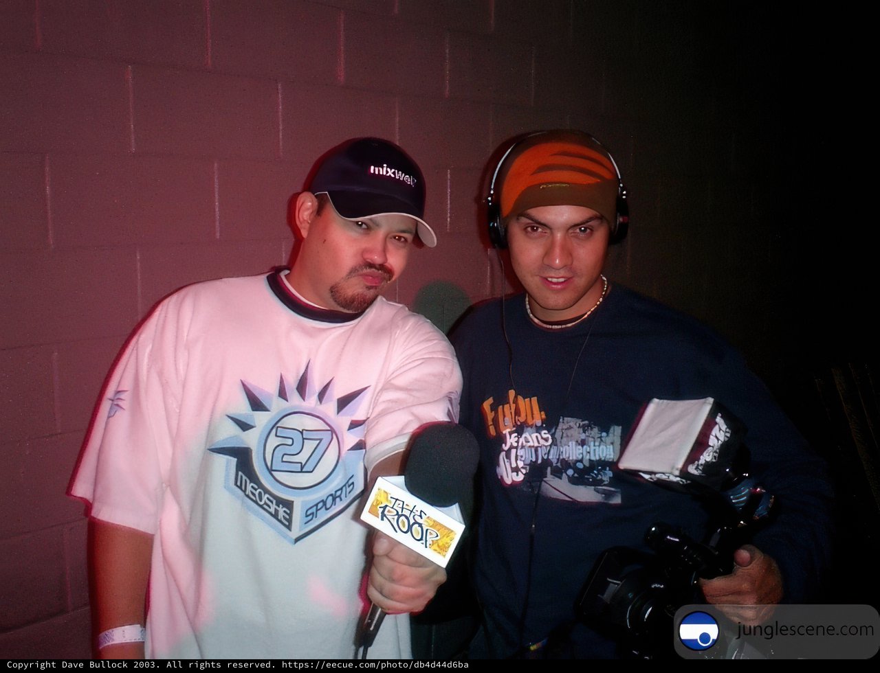 Two Men Holding Microphones and a Baseball Cap