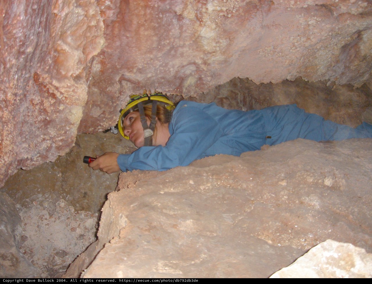 Caver Navigates Tight Underground Passage with Flashlight