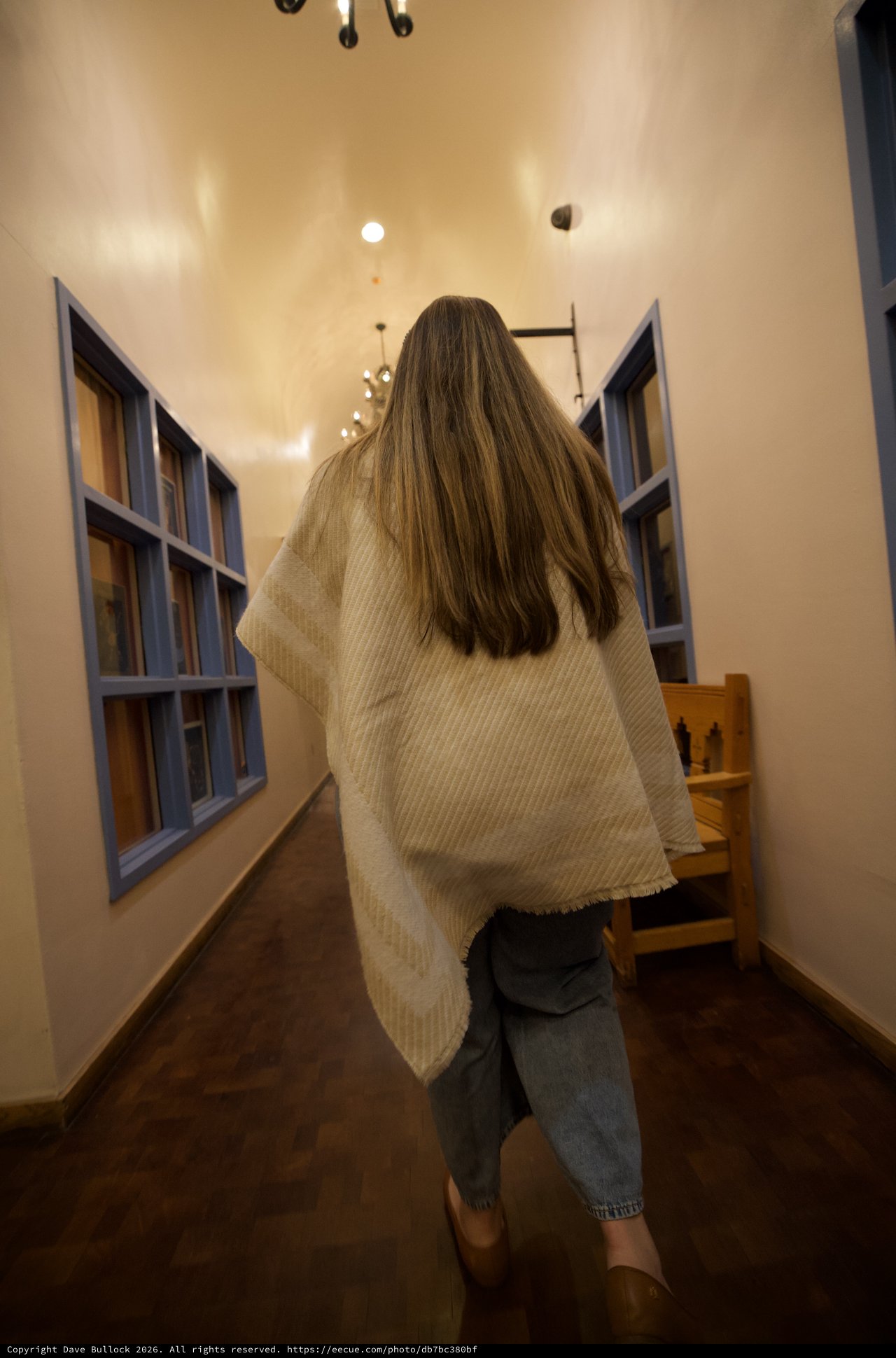 Long-Haired Woman Walking Through Narrow Adobe Hallway
