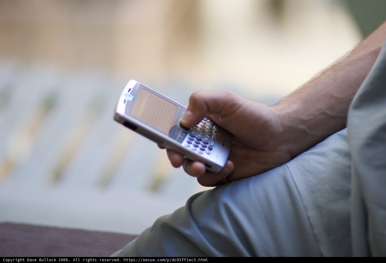 Connected Man Caption: A male adult stays connected with his mobile phone by texting on it, in a 2006 Flexilis shoot.