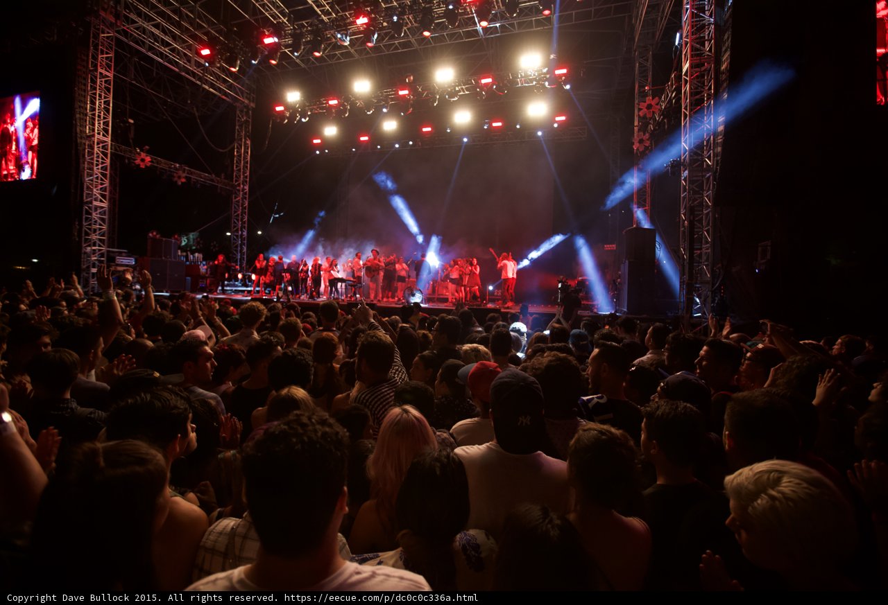 Belle and Sebastian Wide Stage Spotlight Beams Arms Raised Crowd Red White Lighting Ensemble